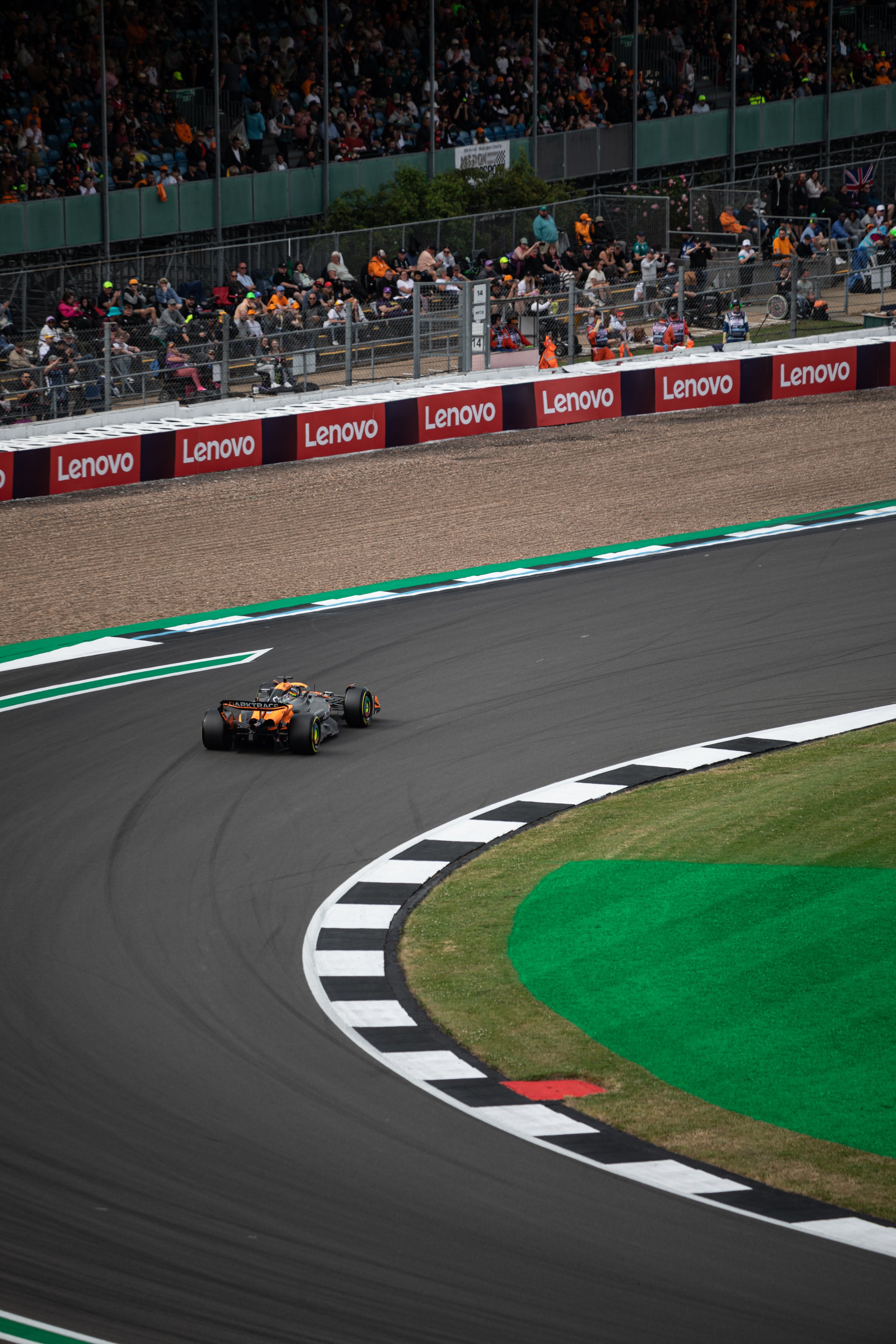 A race car driving on a racetrack with a crowd of spectators in the background.
