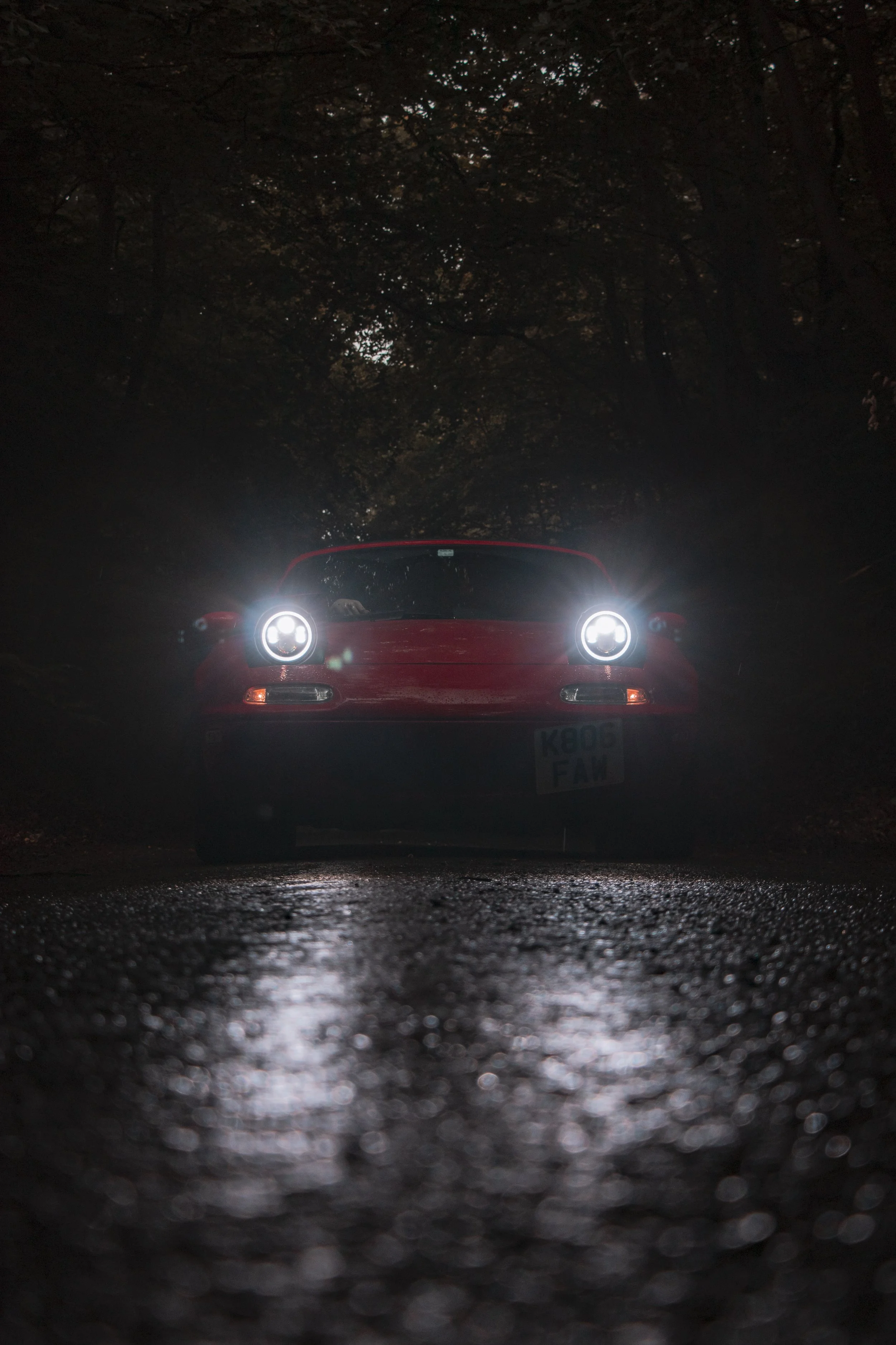 Original Mazda MX5 with headlights on at night time