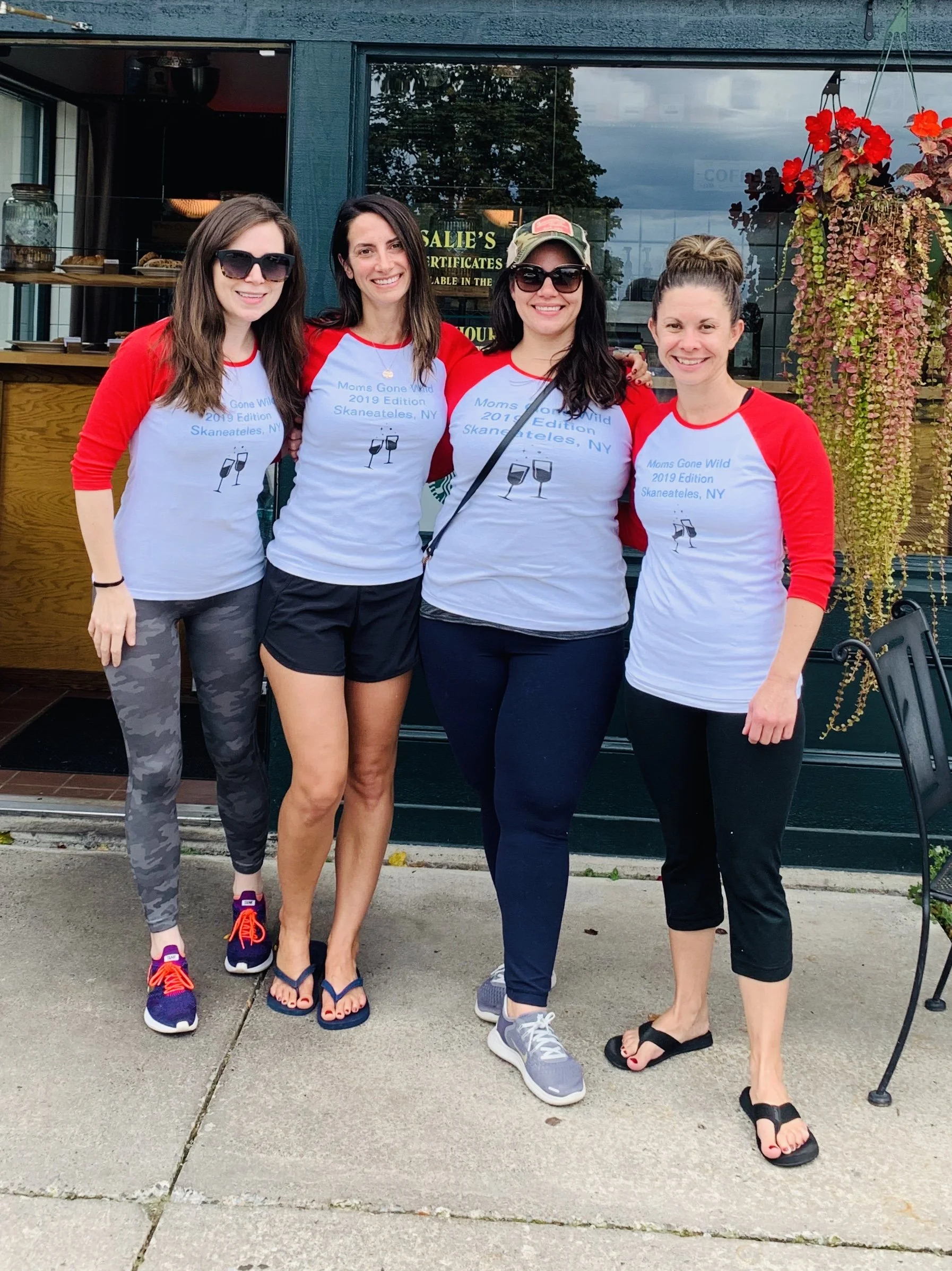 Four women standing together outside a building, smiling at the camera. These women are together for a girls weekend in Skaneateles, NY. They are getting coffee at Rosalie's restaurant.
