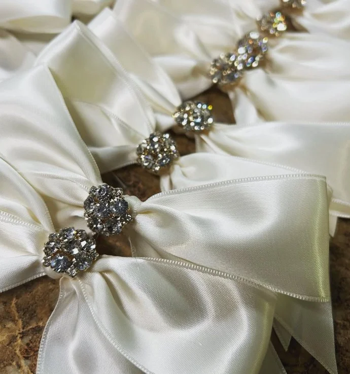 Close-up of white satin bow hair accessories with jeweled embellishments