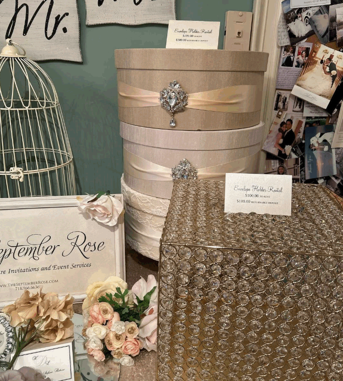 Display of decorative boxes, a birdcage, flowers, and signage for event and wedding services at a rental booth.