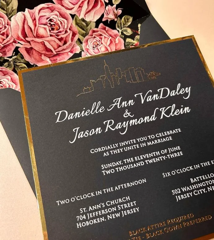 Wedding invitation card with skyline illustration at the top, featuring pink roses in the background.