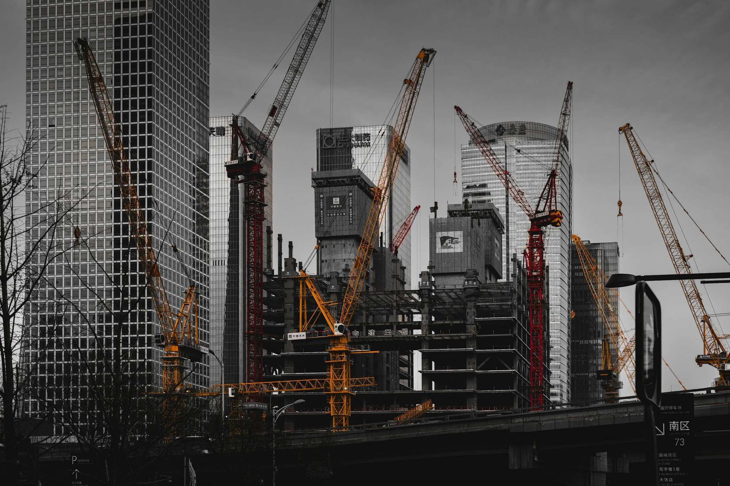 Construction site with multiple cranes and unfinished high-rise buildings in an urban area.
