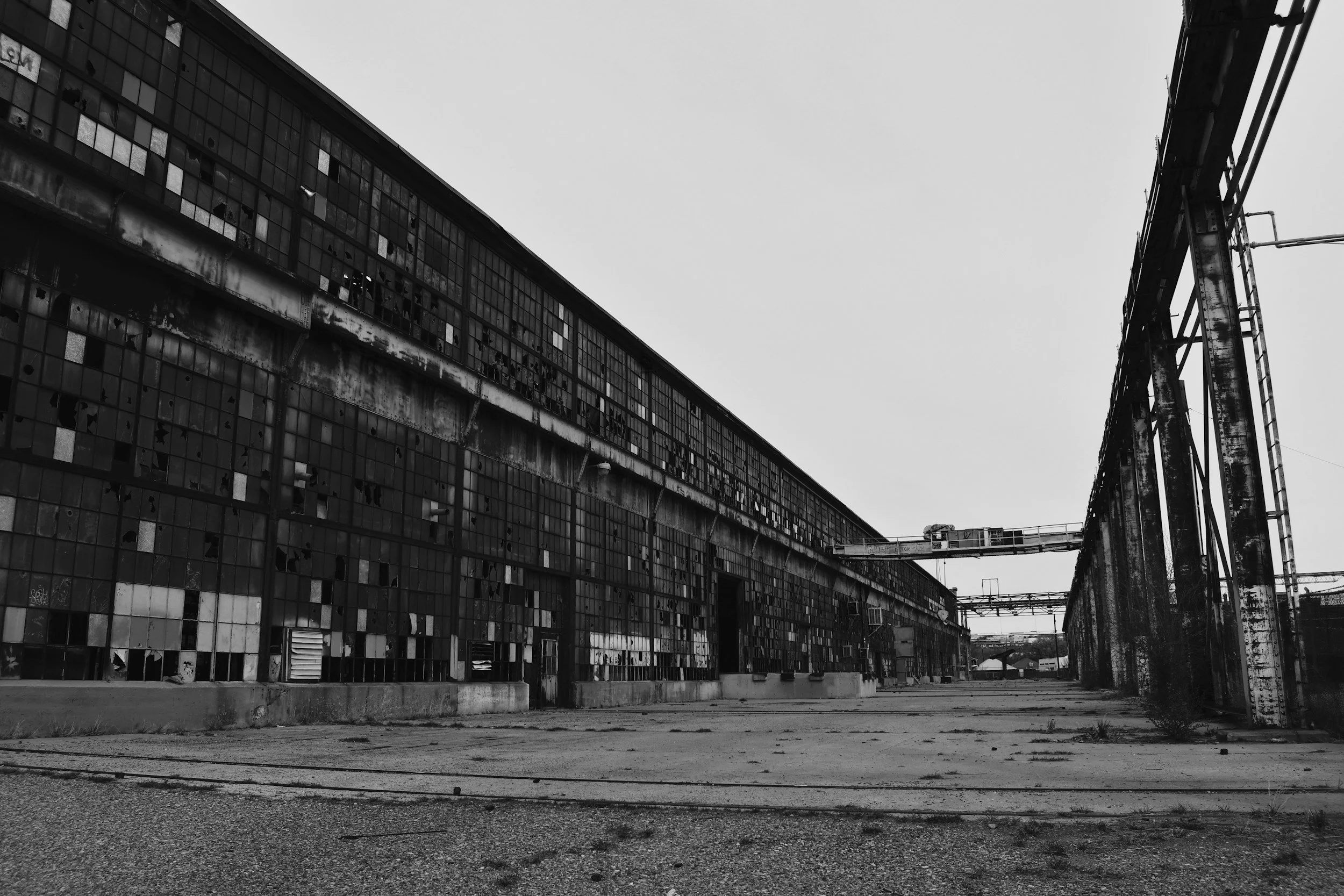 Abandoned industrial building with broken windows and rusted structures in black and white.