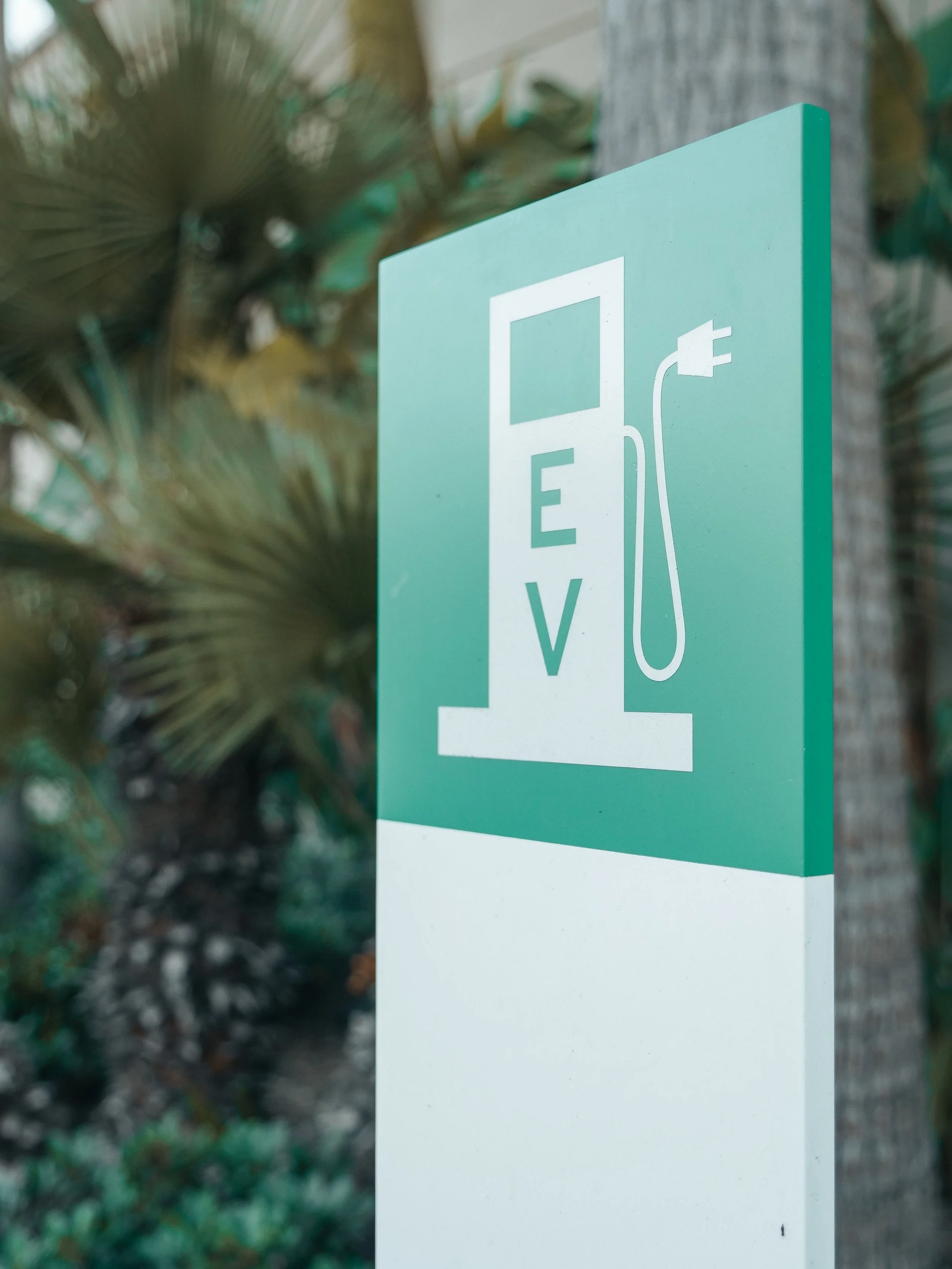 A green electric vehicle charging station with a white outline of a car and a power plug symbol.