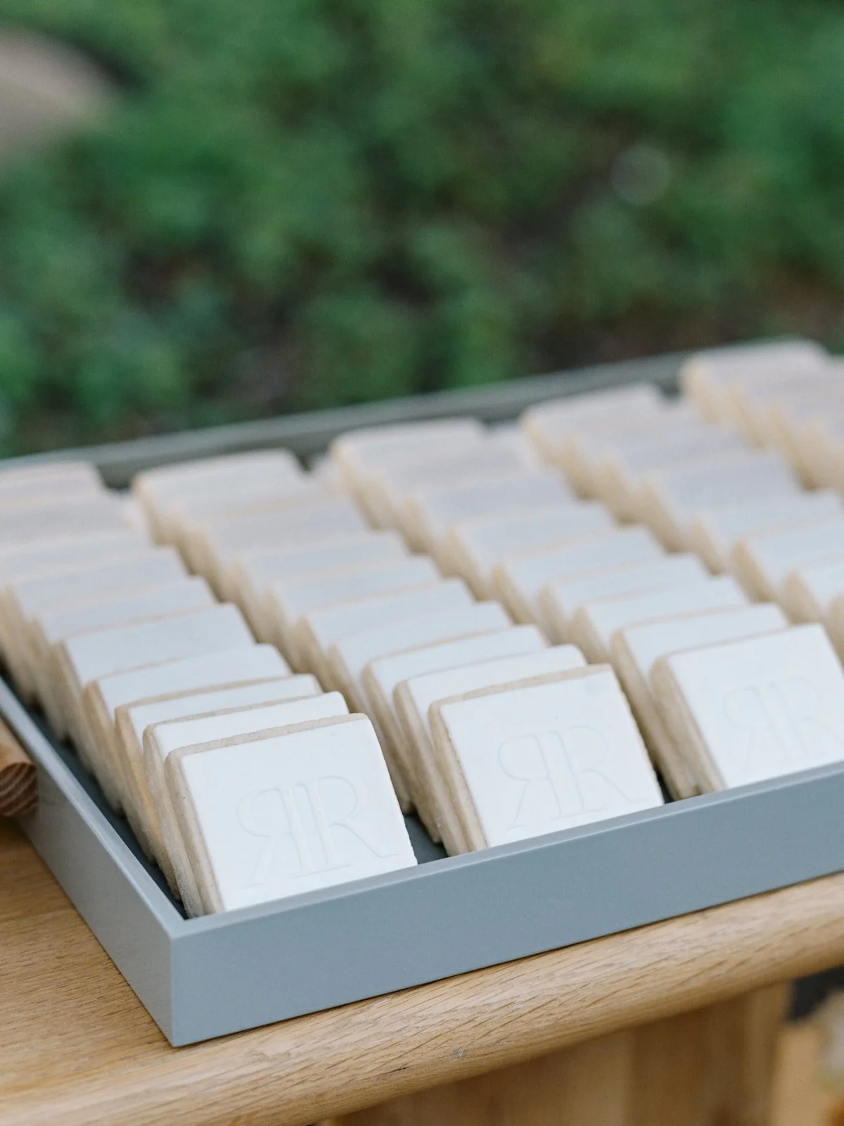 A box of white soap bars with embossed letters 'RR' on each, arranged in rows on a wooden surface.
