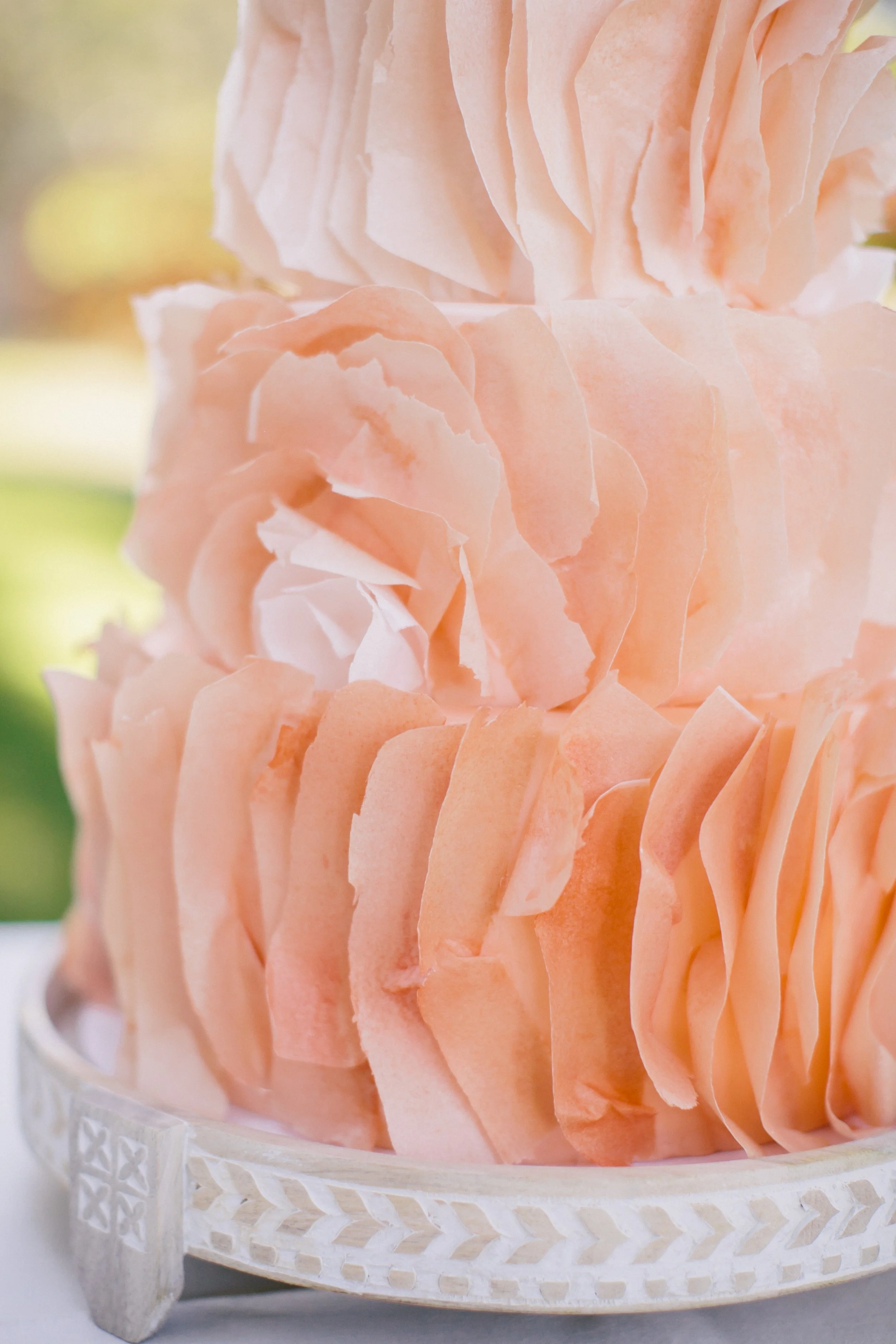 Close-up of pink layered cake with ruffled icing.