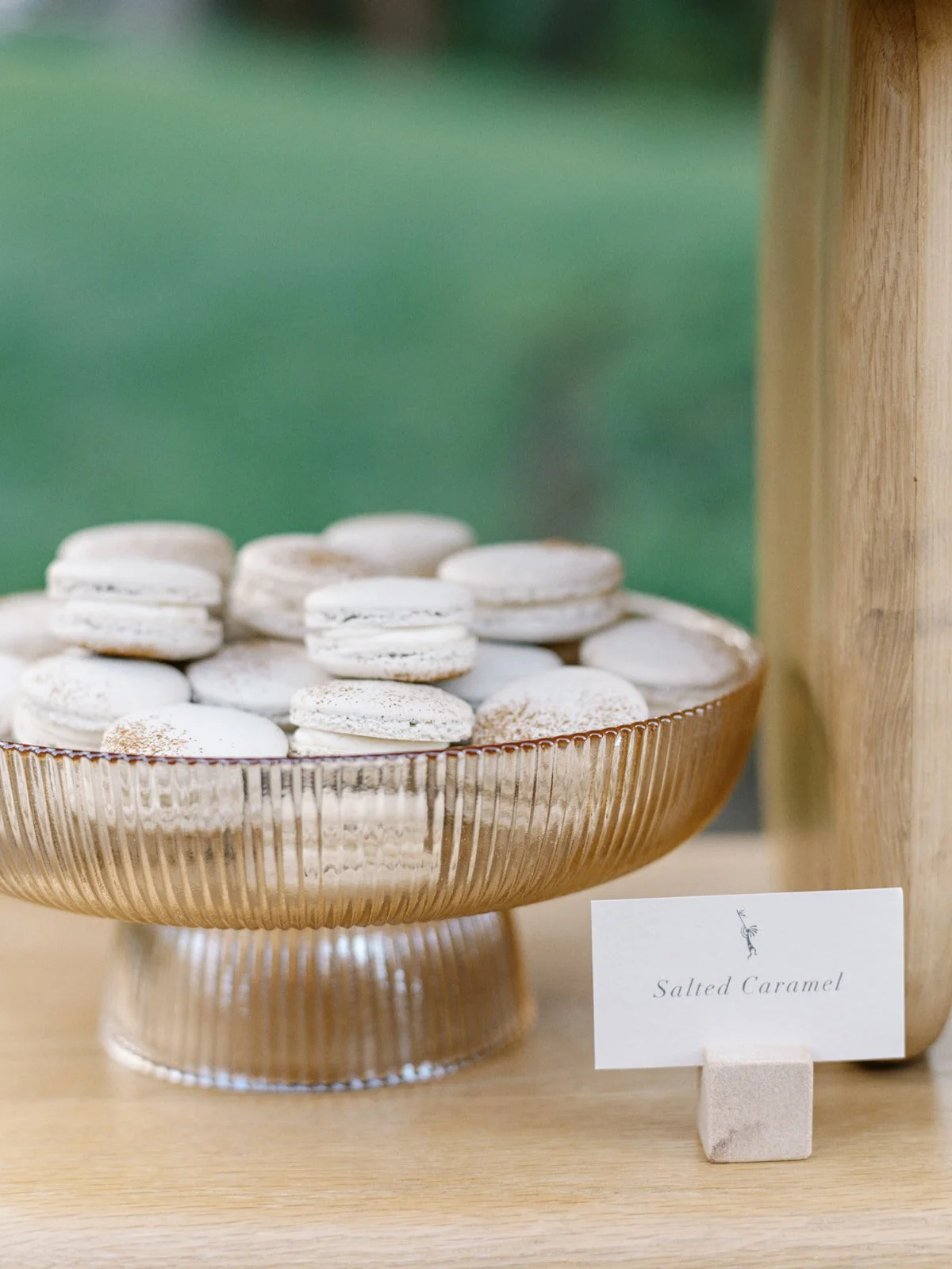 Appetizer display of white salted caramel macarons in a decorative glass bowl with a sign reading 'Salted Caramel'.