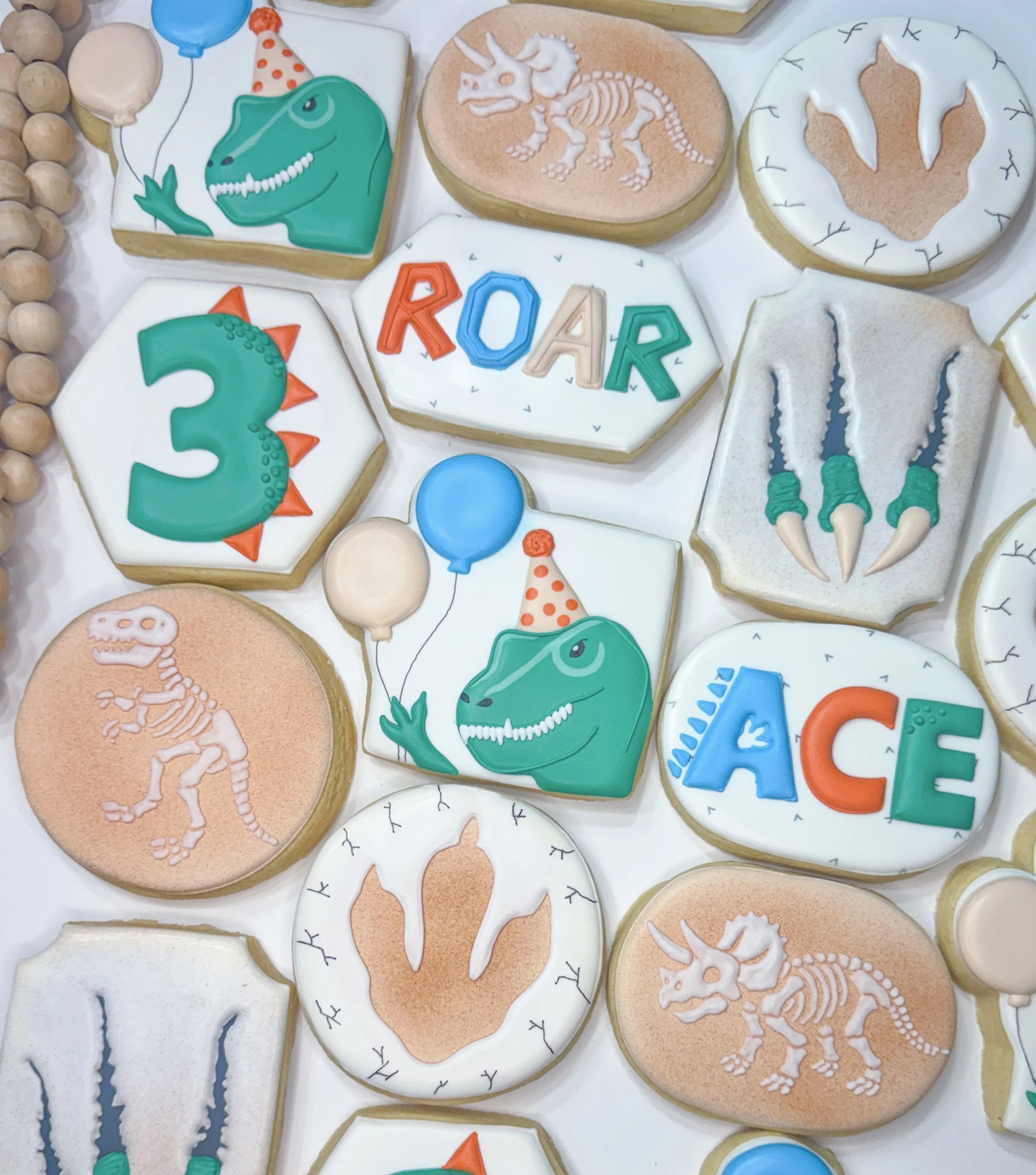 Decorated cookies with dinosaurs, skeletons, and words spelling out 'ROAR' on a white background.