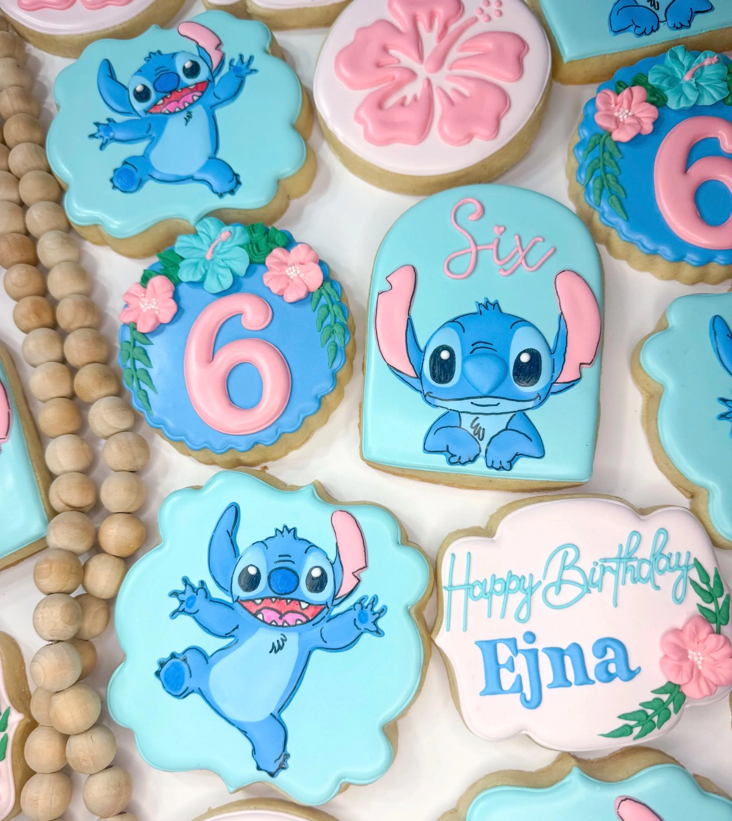 Colorful birthday cookies decorated with characters from Disney's Lilo & Stitch, pink flowers, and messages for a sixth birthday celebration.