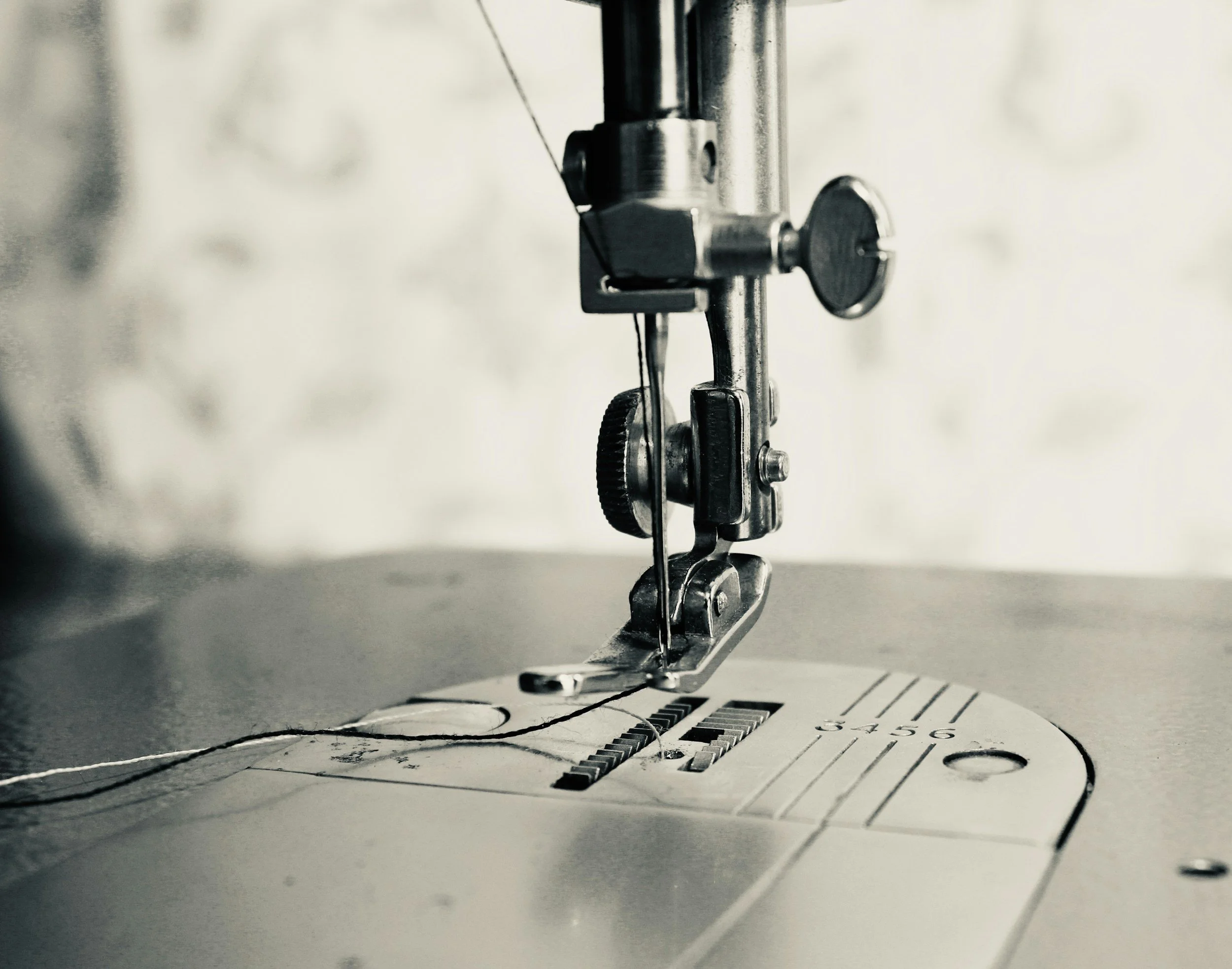 Close-up of the sewing machine needle, presser foot, and fabric with measurement markings.