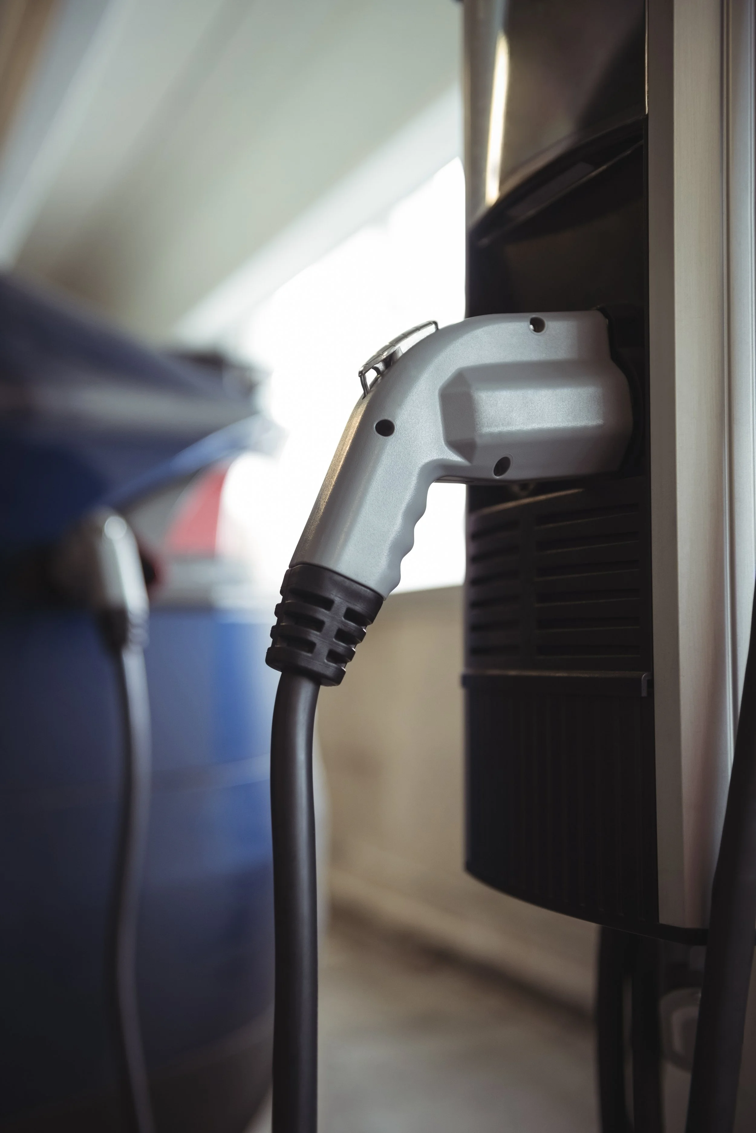 Close-up of an electric vehicle charging plug inserted into a charging station.
