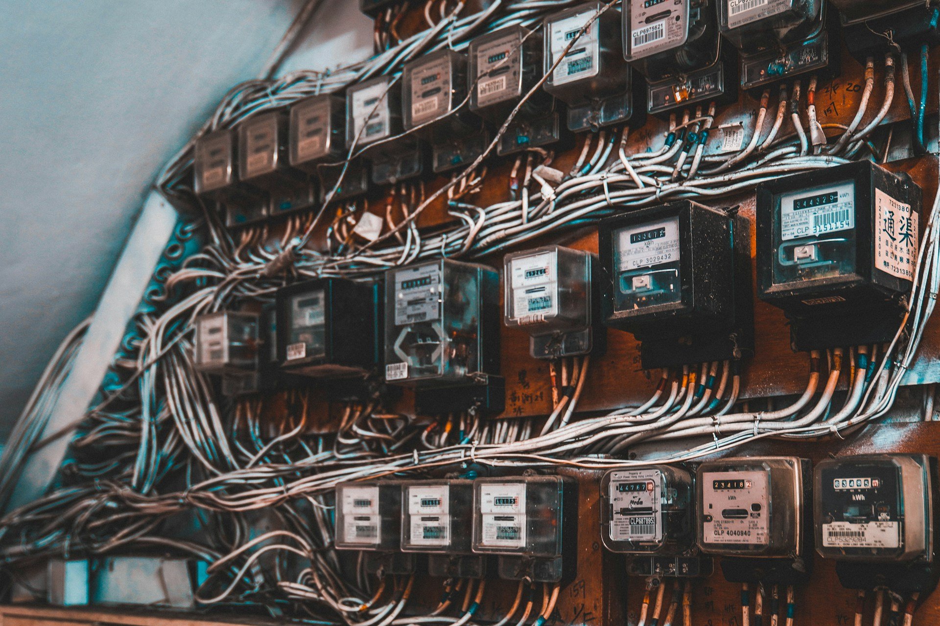 Multiple electrical meters and wires mounted on a wooden panel.