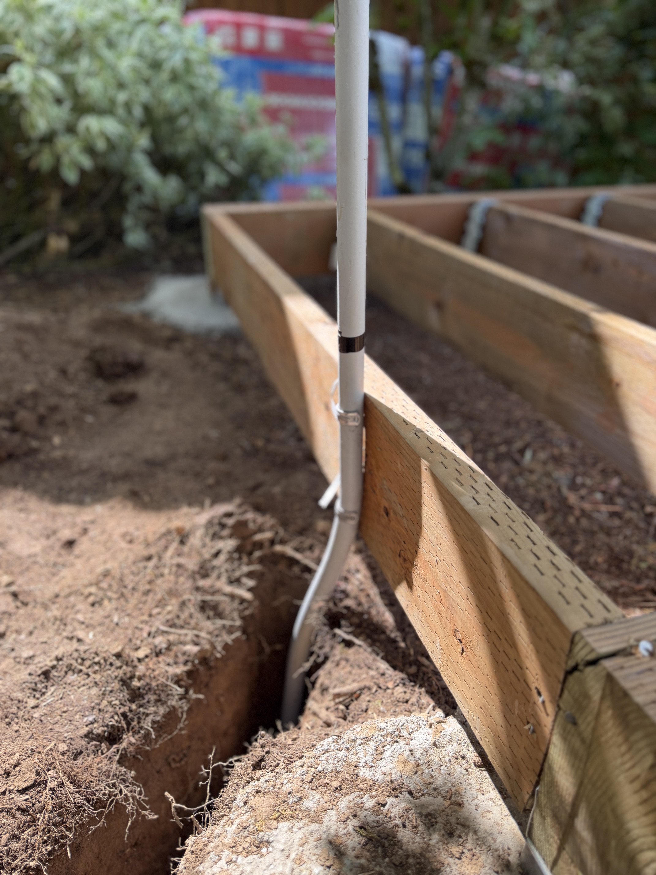 Close-up of the new 240V circuit conduit run from the panel to the sauna, trenched underground in a Beaverton backyard.