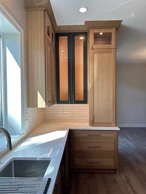 Glass-front cabinet accent lighting above a tile backsplash in a Portland kitchen remodel