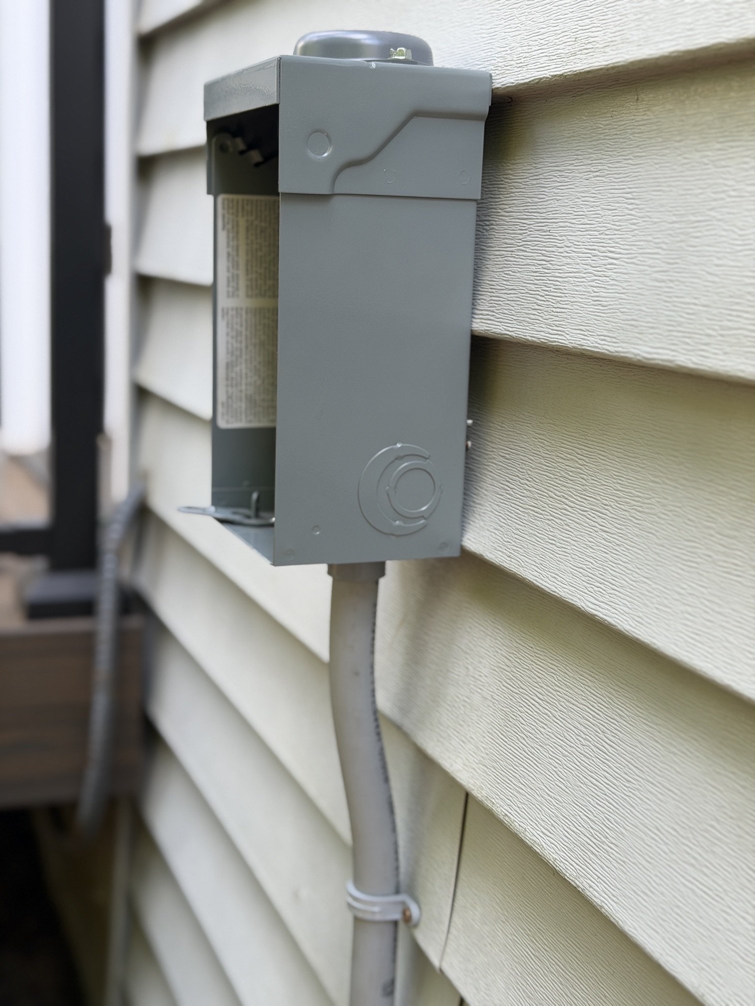 New exterior disconnect box mounted on the home's siding for the sauna's dedicated 240V circuit, before wiring was connected.