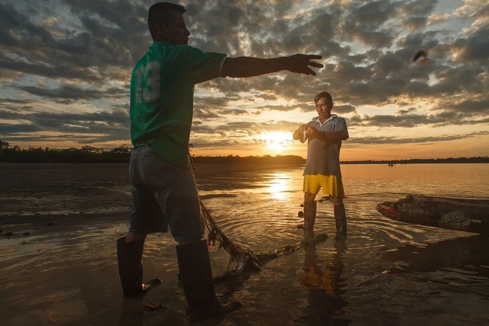 Two fishermen pull a net from the water and inspect their catch along the banks of the Amazon River at sunrise, Friday, June 22, 2012, near Iquitos, Peru.