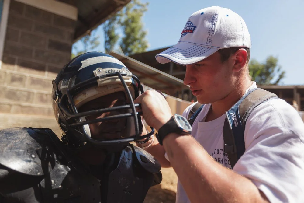 St. Paul’s high school student-athlete Travis Wood inspects a donated helmet alongside local players during a Fellowship of Christian Athletes (FCA) youth football clinic at Mountain Park Academy, Monday, Jan. 2, 2012, in Nakuru, Kenya.