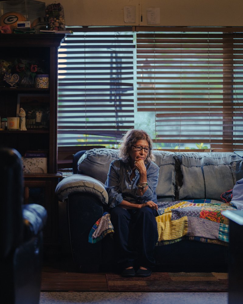 Community volunteer Maria sits on her sofa following a ten-hour shift registering families during an early-morning mobile food distribution clinic at the Boynton Beach Mall, Saturday, July 12, 2025, at her home in Lake Worth, Florida.