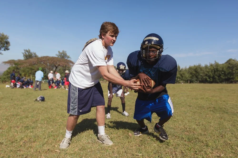 St. Paul’s high school student-athlete Keifer Rawlings hand-positions a football into the chest of a local player during a drill at a Fellowship of Christian Athletes (FCA) youth football clinic at Mountain Park Academy, Wednesday, Jan. 4, 2012, in N