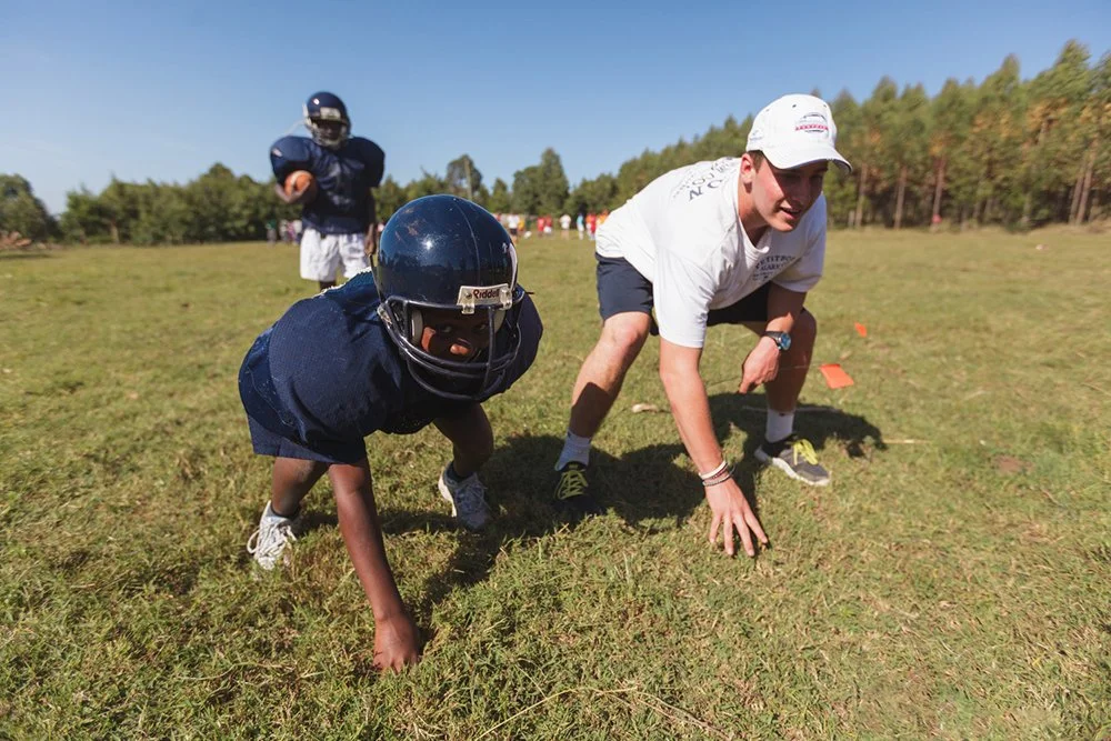 St. Paul’s high school student-athlete Travis Wood demonstrates a three-point stance alongside a local youth player during a line scrimmage drill at a Fellowship of Christian Athletes (FCA) football clinic at Mountain Park Academy, Wednesday, Jan. 4,