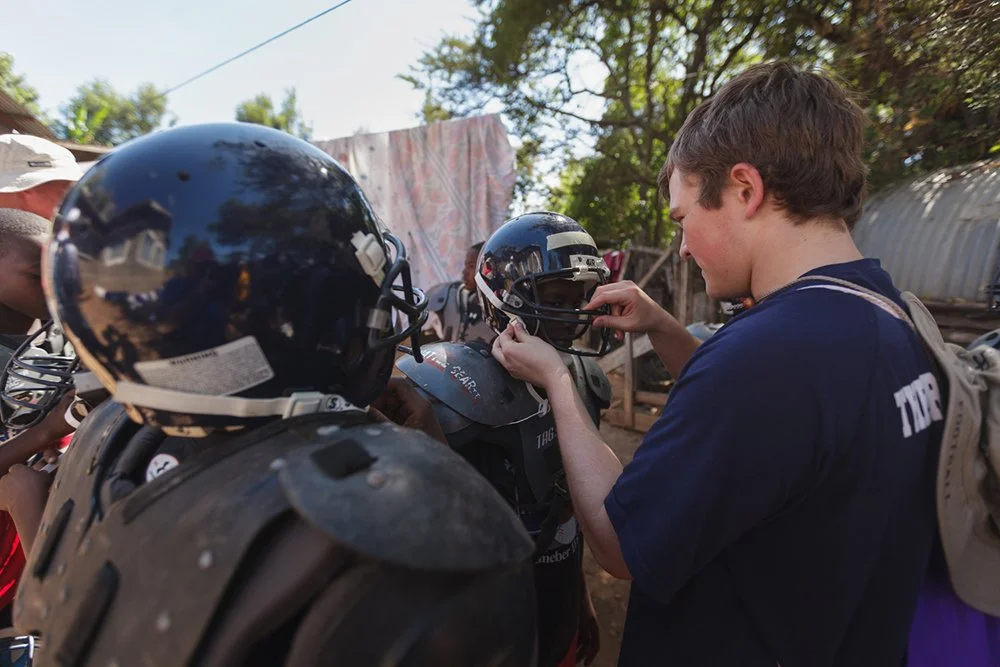 St. Paul’s high school student-athlete Keifer Rawlings inspects a donated helmet alongside local players during a Fellowship of Christian Athletes (FCA) youth football clinic at Mountain Park Academy, Monday, Jan. 2, 2012, in Nakuru, Kenya.