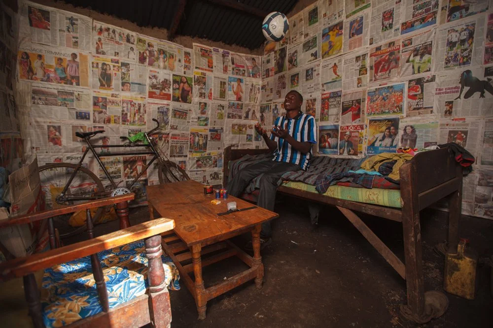 A young man tracks a soccer ball tossed in the air while inside his bedroom, where the walls are lined with newspaper sports clippings, Wednesday, Jan. 4, 2012, near Nakuru, Kenya.