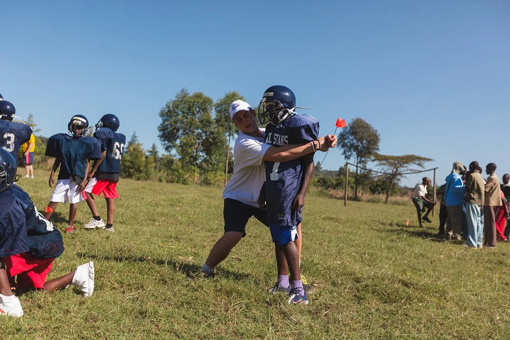 St. Paul’s high school student-athlete Travis Wood demonstrates body positioning during a defensive drill with a local youth player at a Fellowship of Christian Athletes (FCA) football clinic at Mountain Park Academy, Wednesday, Jan. 4, 2012, in Naku