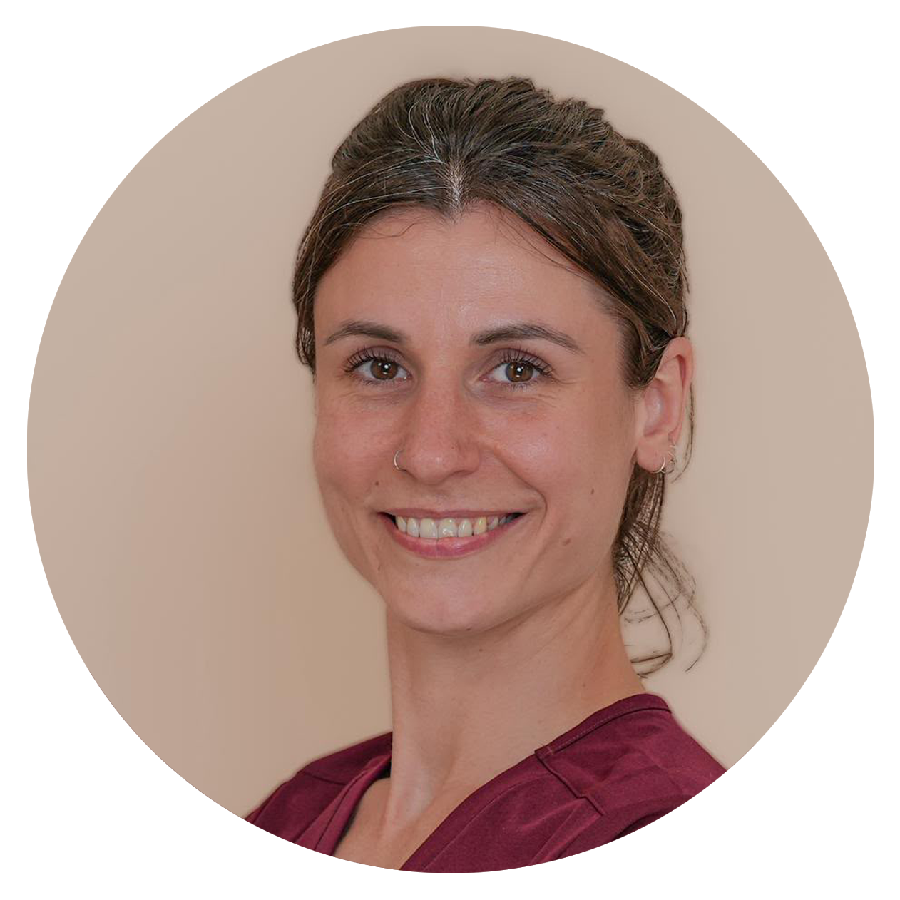 Portrait d'une femme souriante avec des cheveux bruns relevés, portant un haut bordeaux, contre un fond beige.