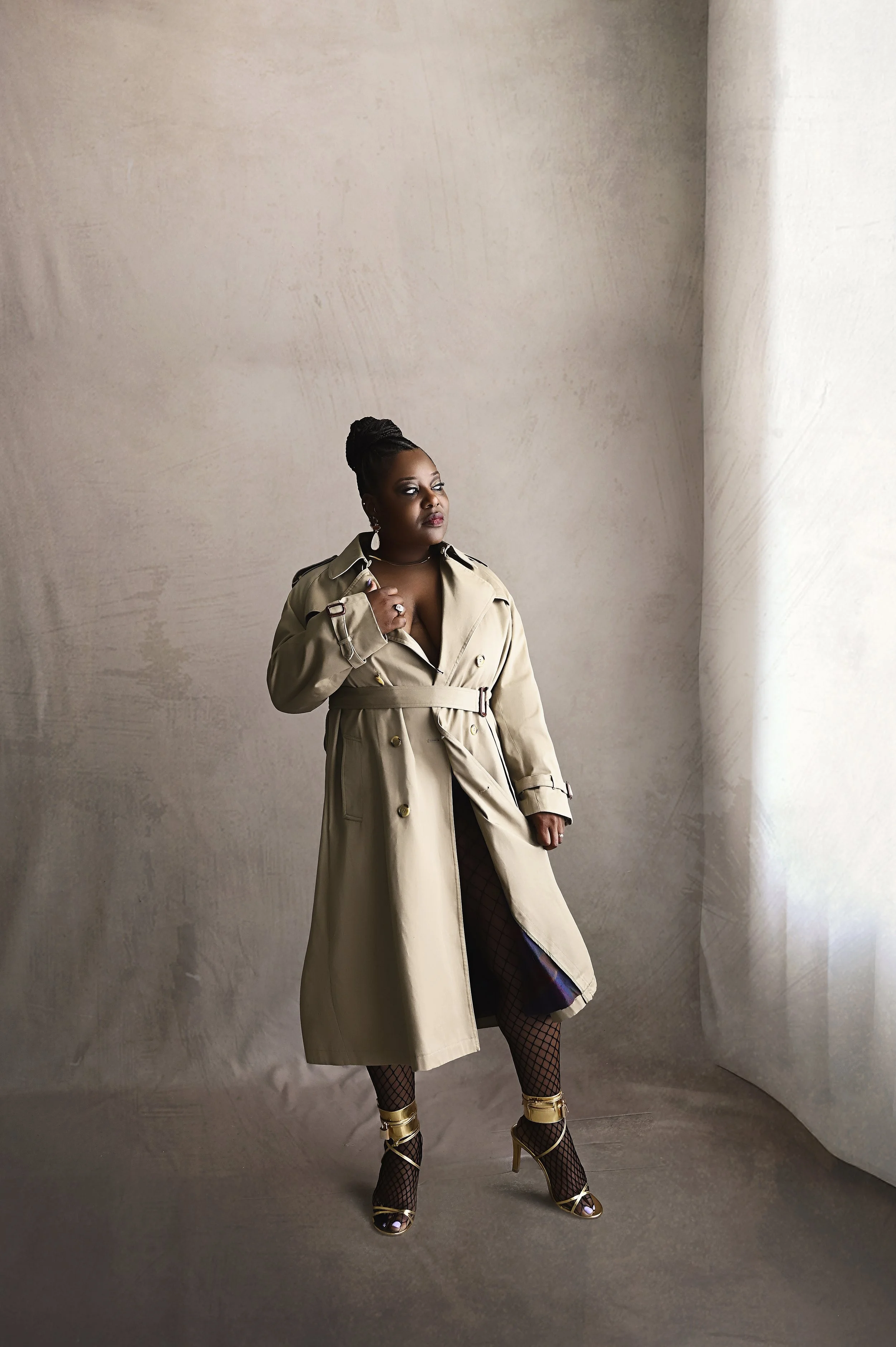 Full body luxury boudoir portrait featuring trench coat styling and fishnet stockings