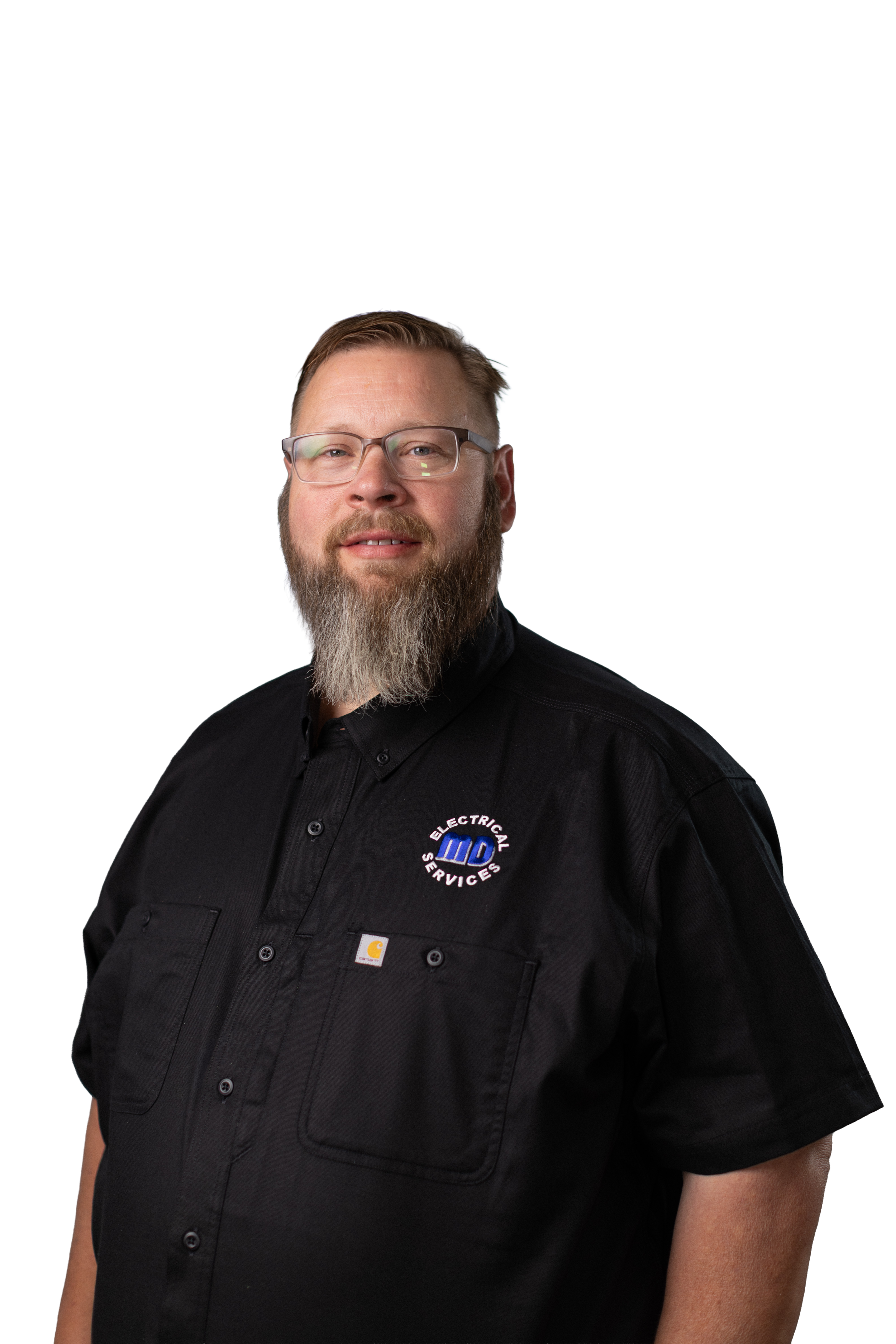 A man with glasses and a beard wearing a black work shirt with a logo for electrical services.