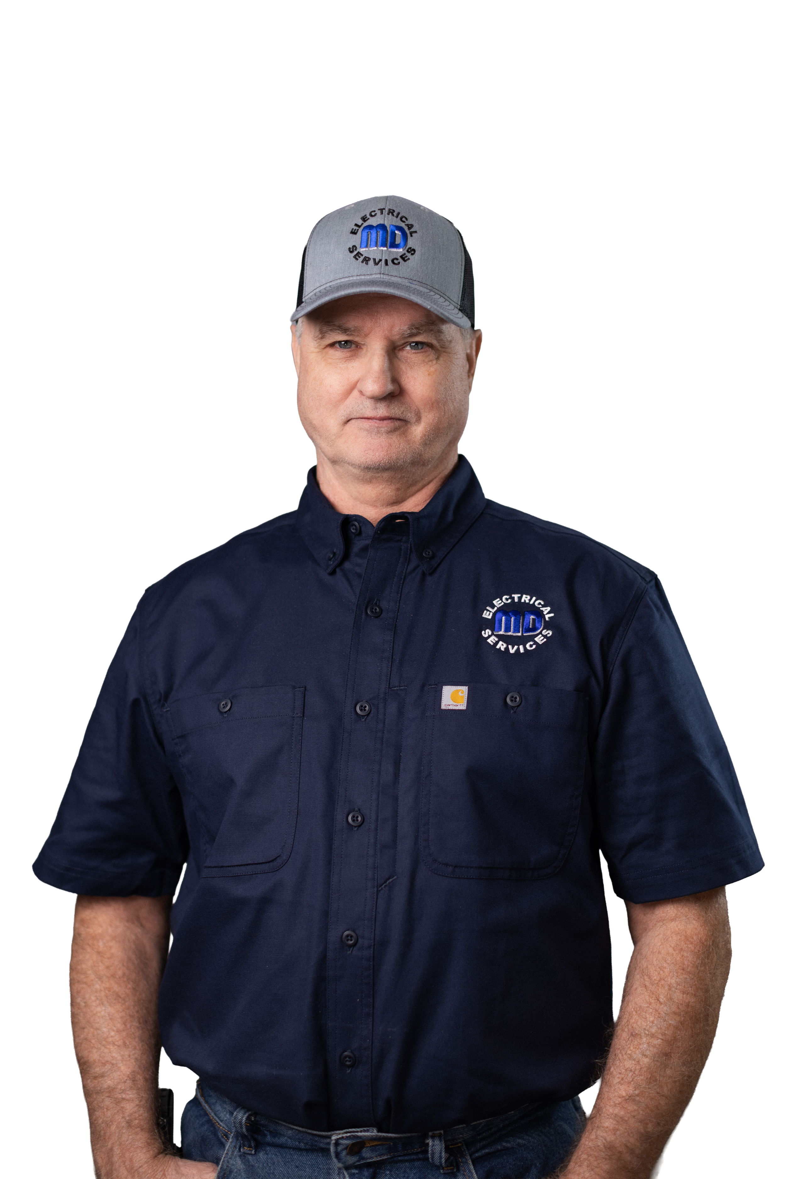 A man wearing a gray baseball cap with the logo 'MD Electrical Services' and a navy blue work shirt with the same logo, standing against a black background.