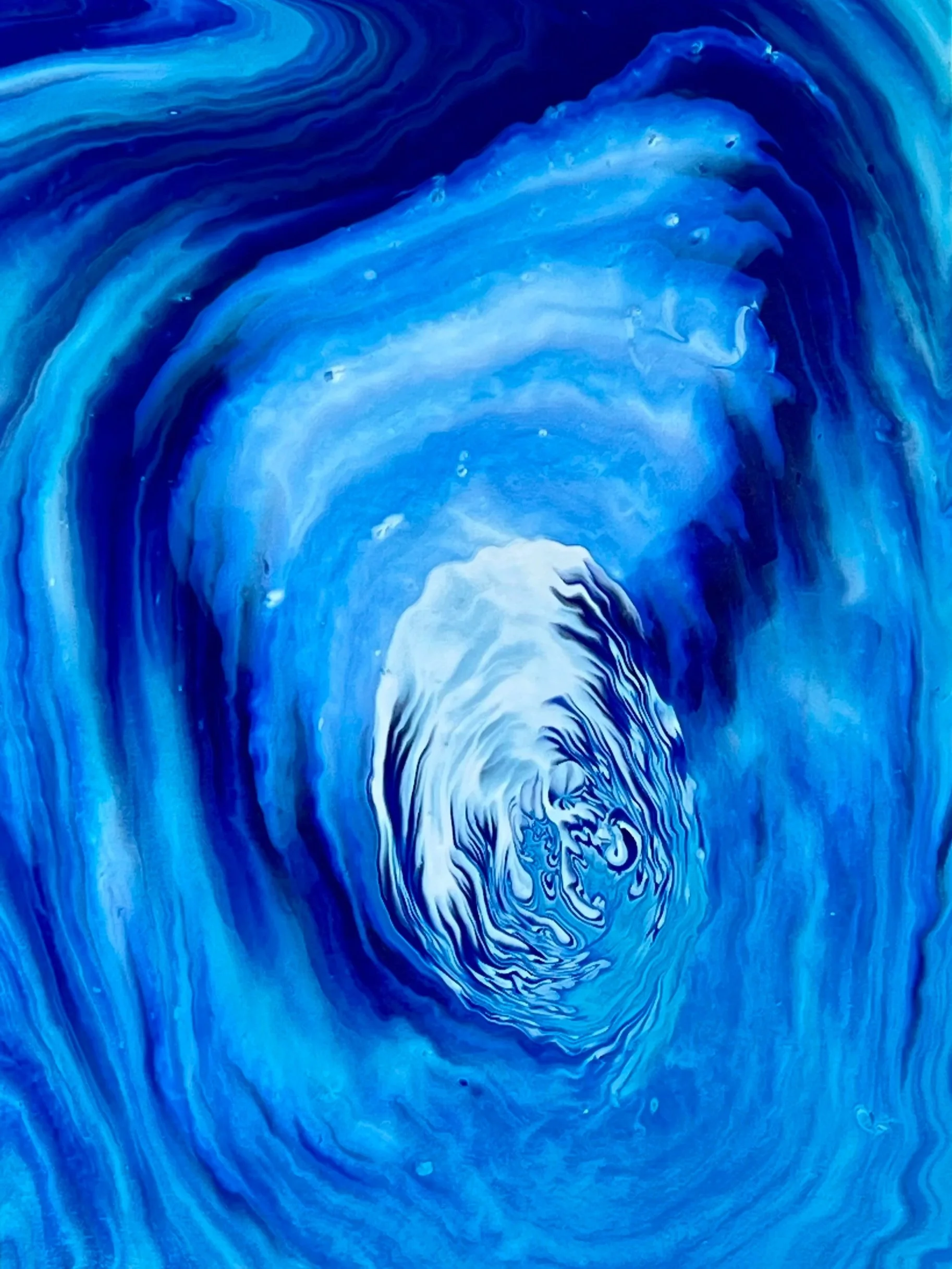 Swirling blue and white abstract pattern resembling a whirlpool or ocean currents.