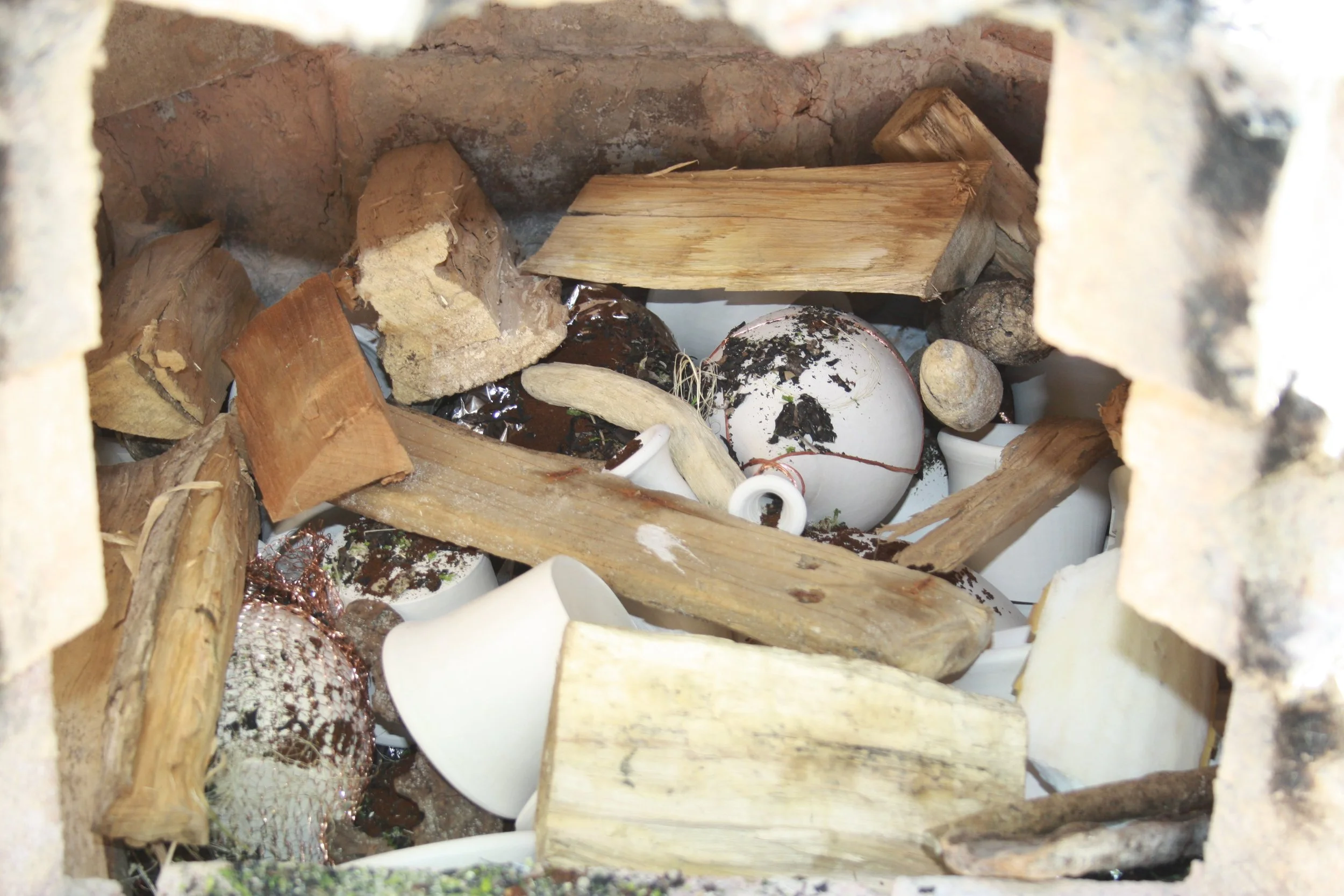 Inside the pottery kiln  filled with broken ceramic pieces, wood, and debris.