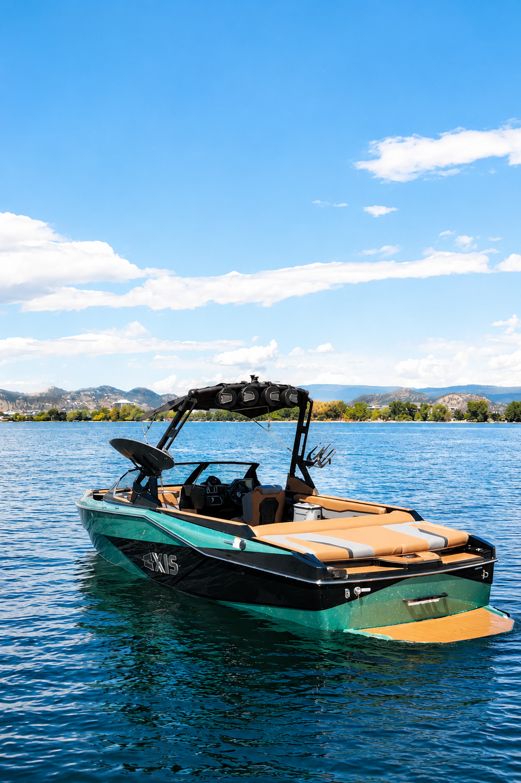 A modern motorboat floating on a lake under a blue sky with some clouds, with mountains and trees in the background.