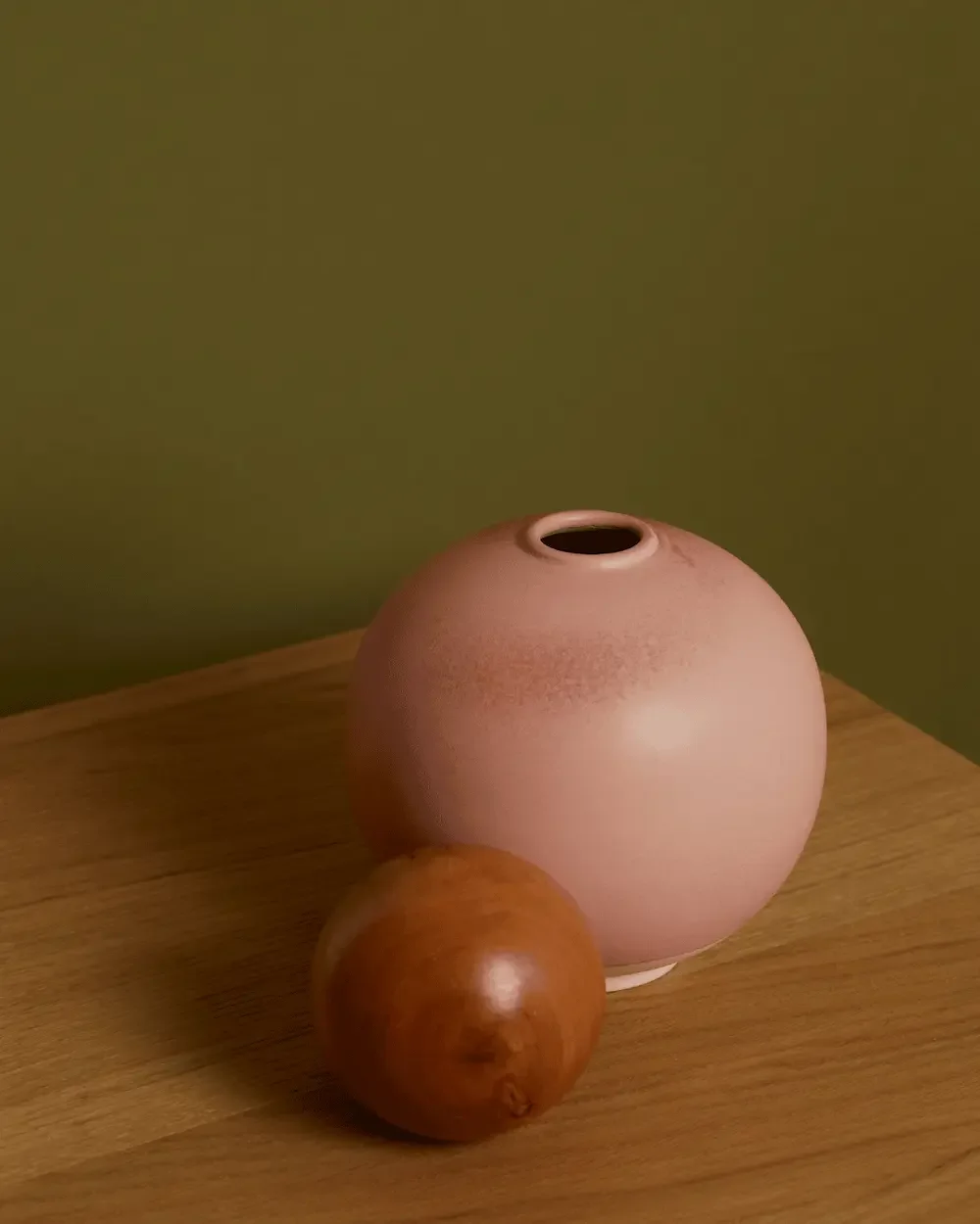 Pink ceramic vase and wooden sphere on a wooden table in a counselling room.