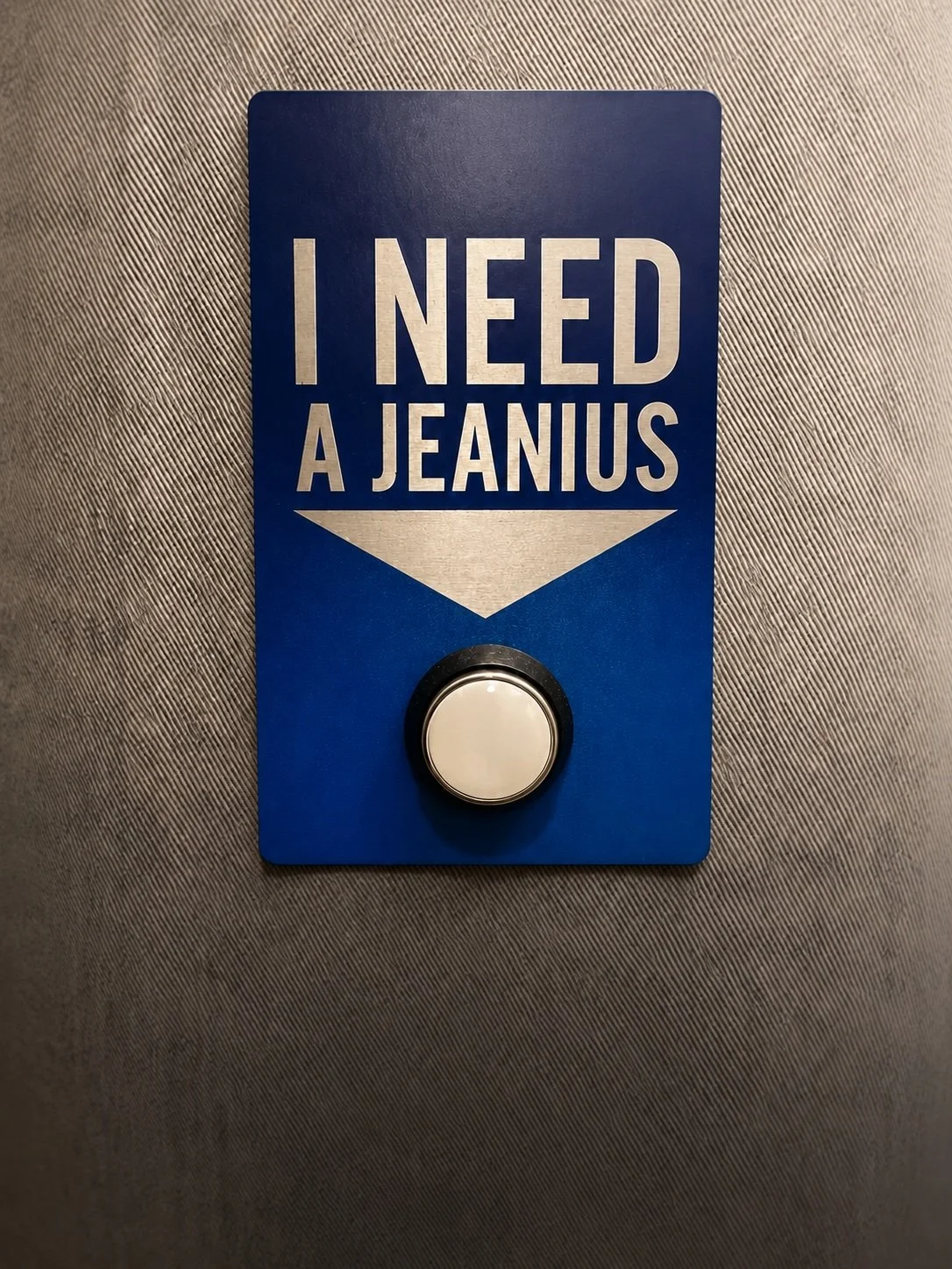 “I NEED A JEANIUS” sign on a Selfridges changing-room wall.