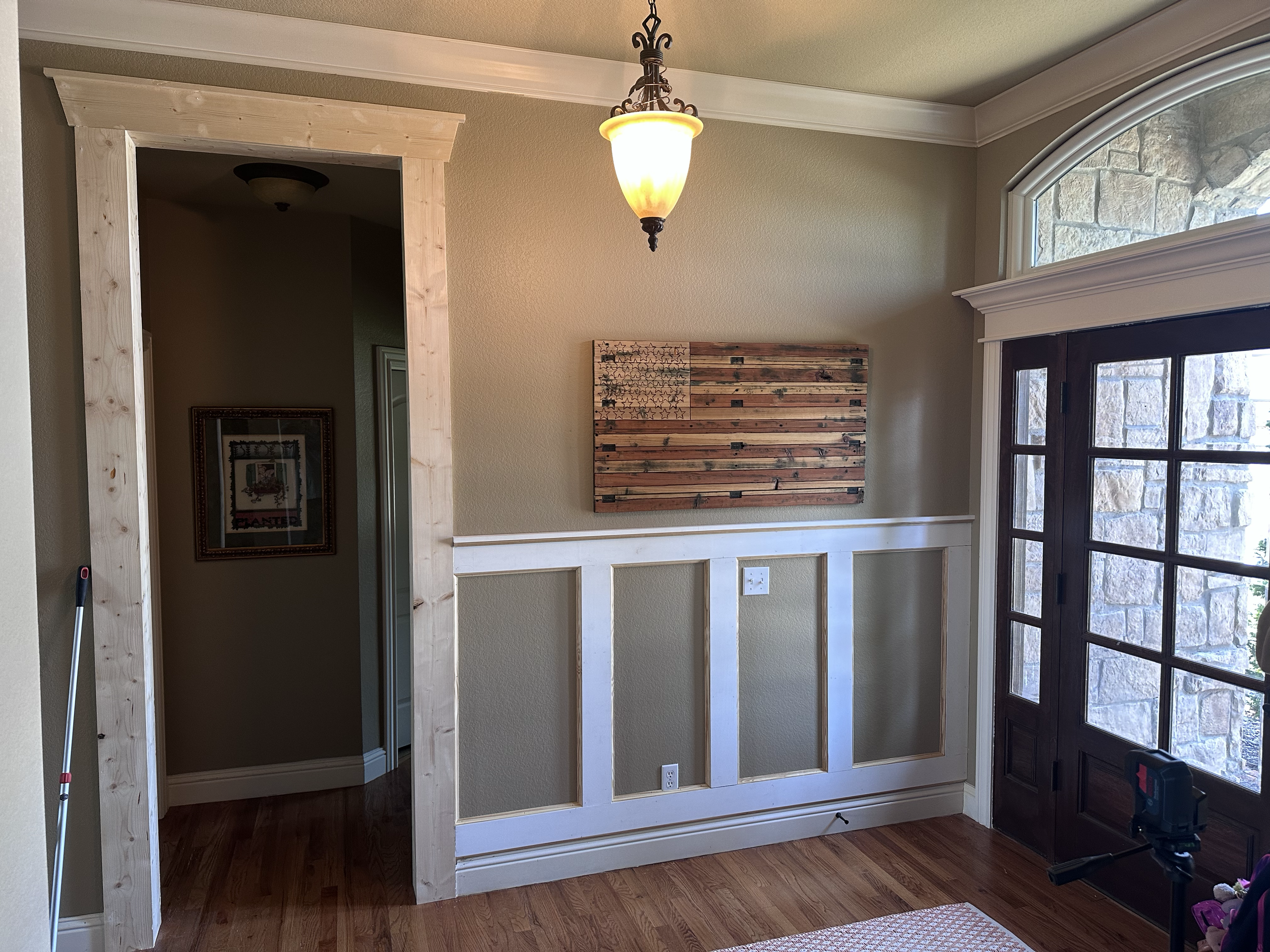 Living room with a partially constructed wall framing, window, and wooden flooring.