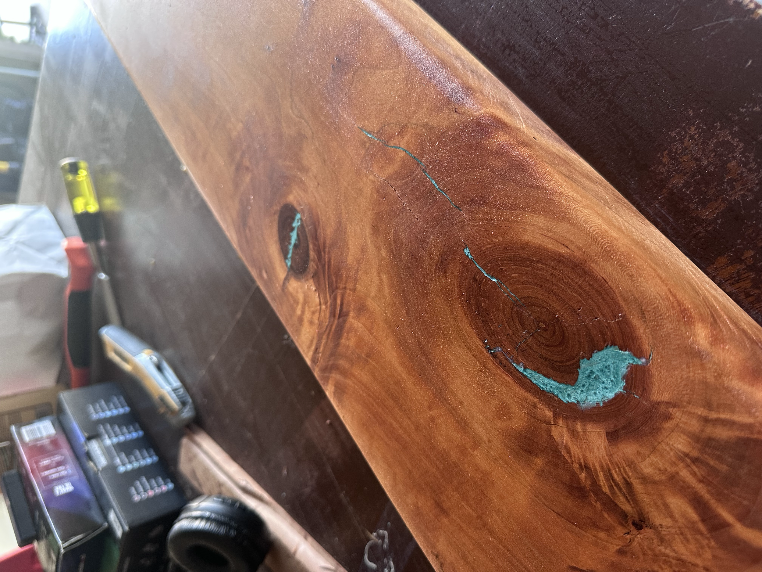 Close-up of a wooden surface with a crack or split, showing blue-greenish inlay in the crack.