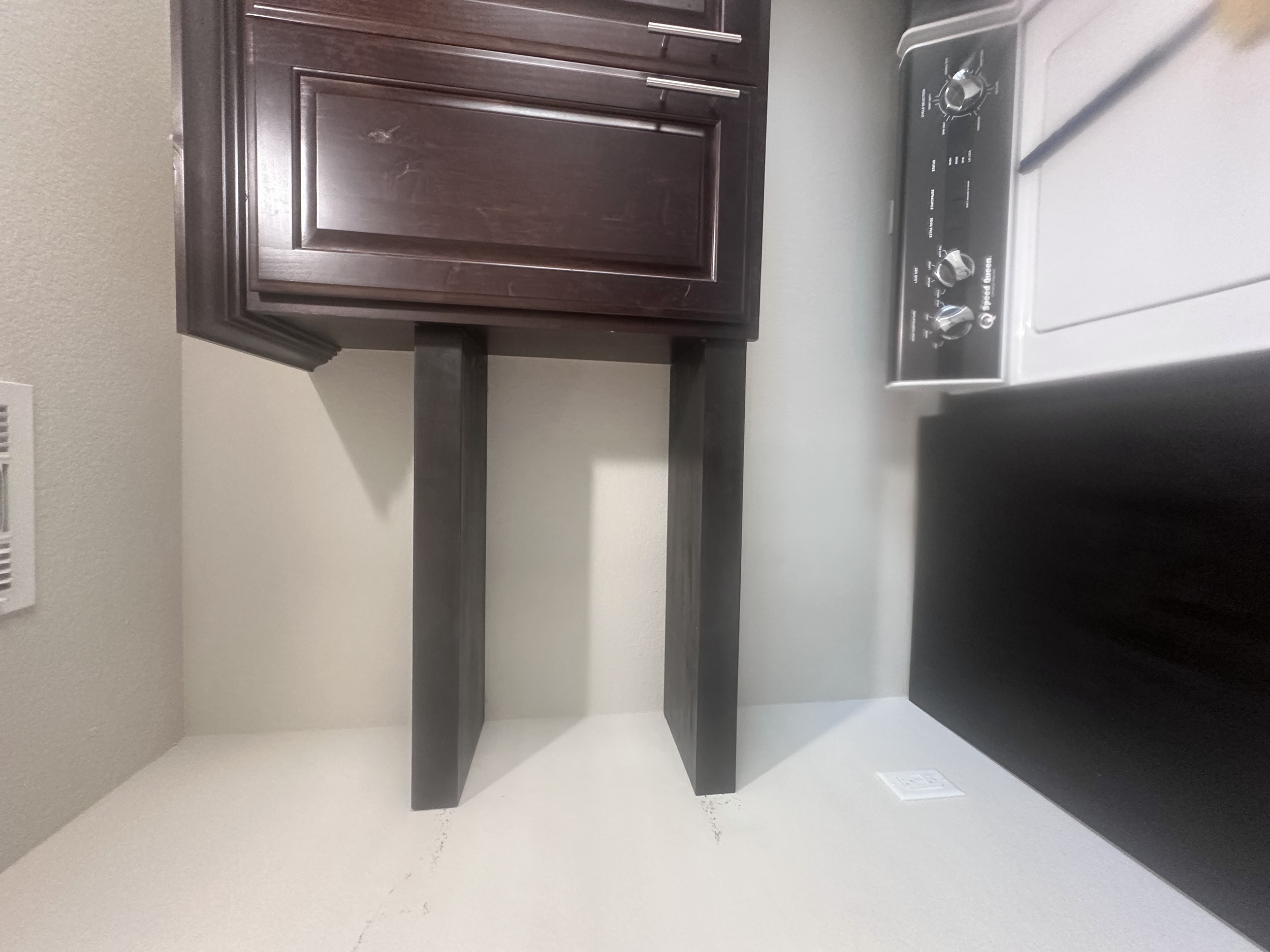 A kitchen corner with a dark wooden cabinet and a white stove with control knobs.