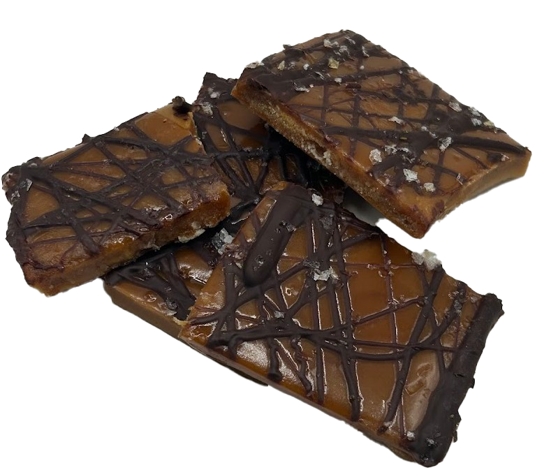 Three caramel-covered chocolate bars with a drizzle of dark chocolate on top, stacked on a reflective surface.
