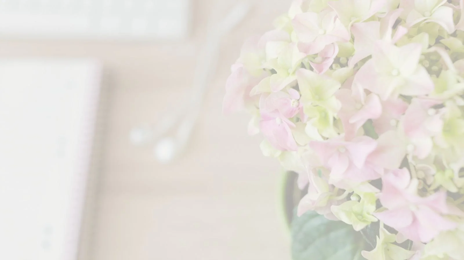 Close-up of a bouquet of pink and green hydrangea flowers in a vase, blurred background.