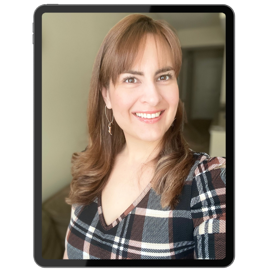 A woman with light brown hair, wearing a plaid shirt and earrings, smiling at the camera in an indoor setting.