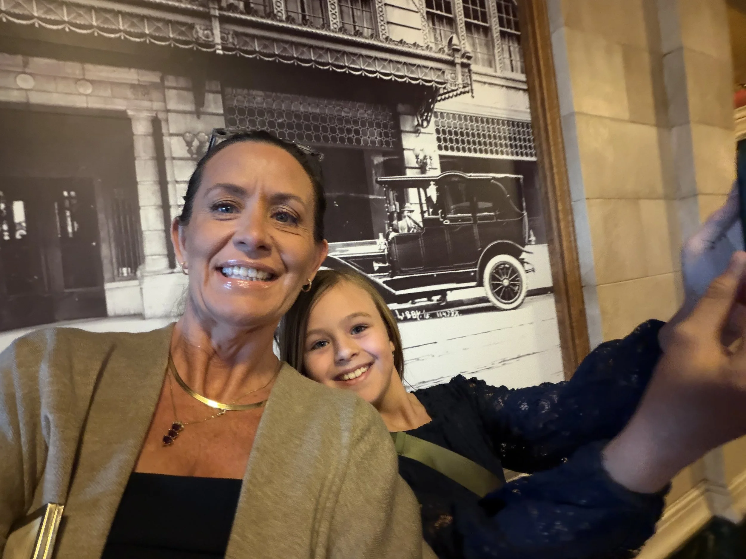 Dr. Meg Ryan, DC smiling with her young daughter, both posed in front of a large vintage black and white photograph
