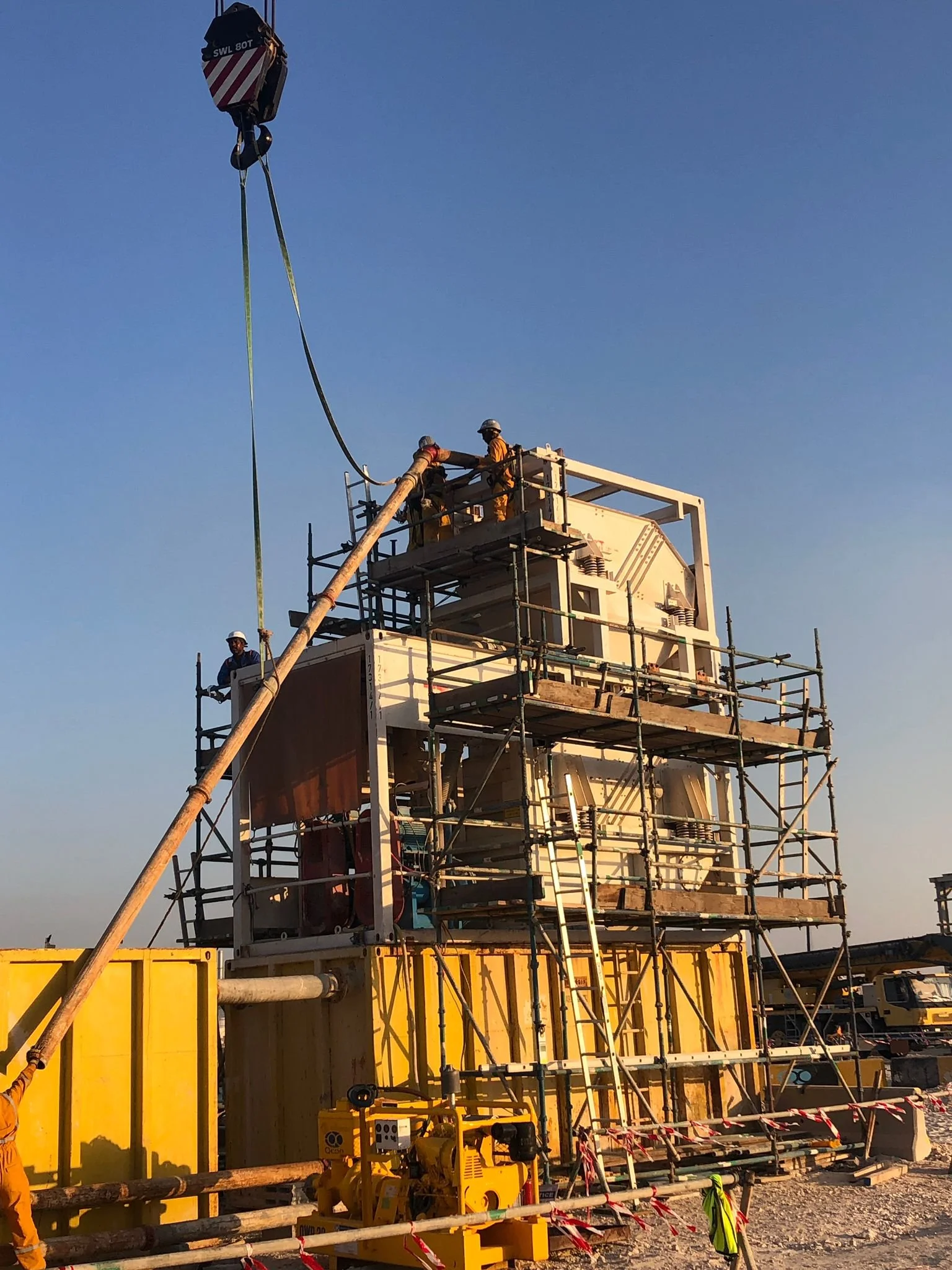 Terra Tunnel Group workers on scaffolding around a large industrial structure and equipment under a crane.