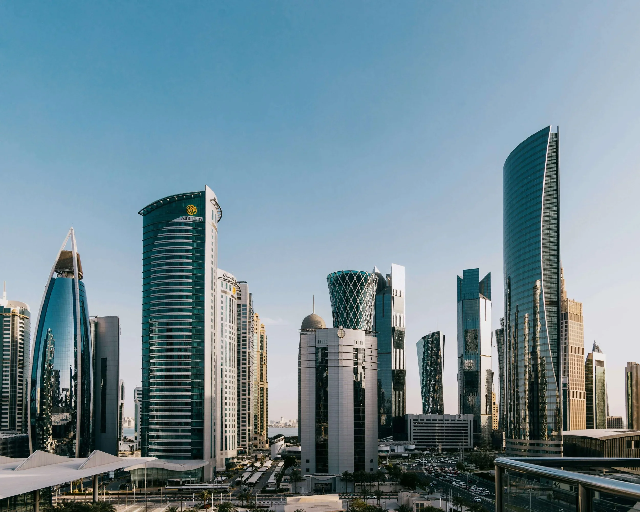Doha's skyline with modern glass skyscrapers, unique architecture, and a clear blue sky.