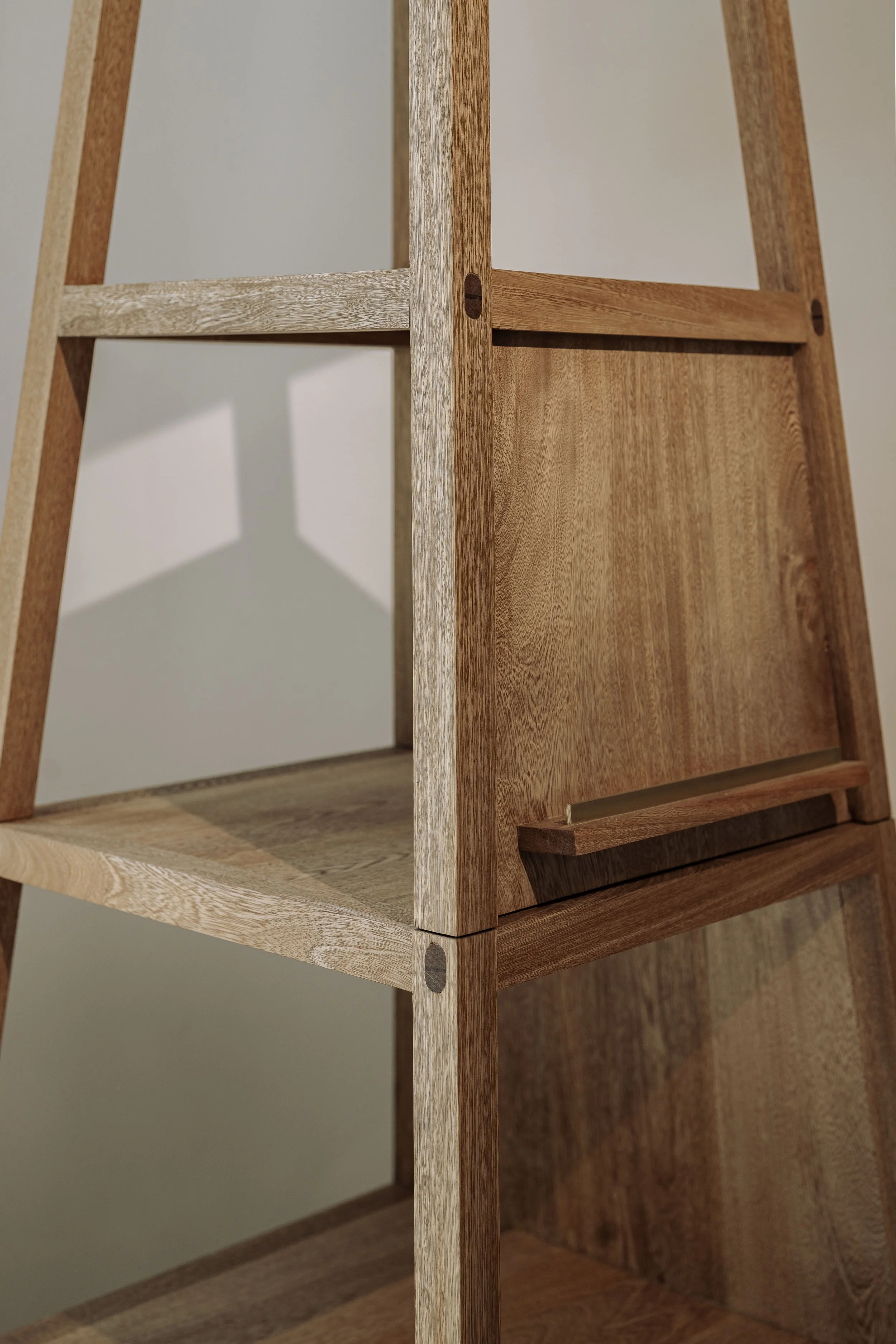 Estantería de madera con varias repisas, hecha de madera clara y oscura, con tornillos visibles en las juntas.