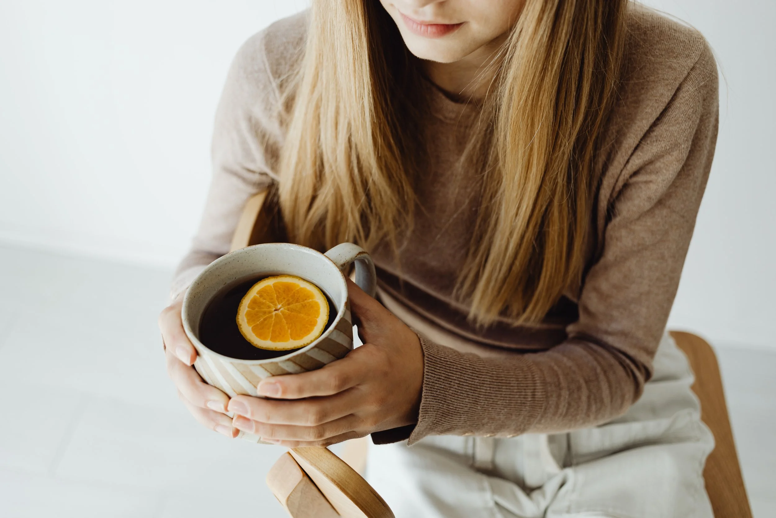 Woman holding a mug of coffee with an orange slice.