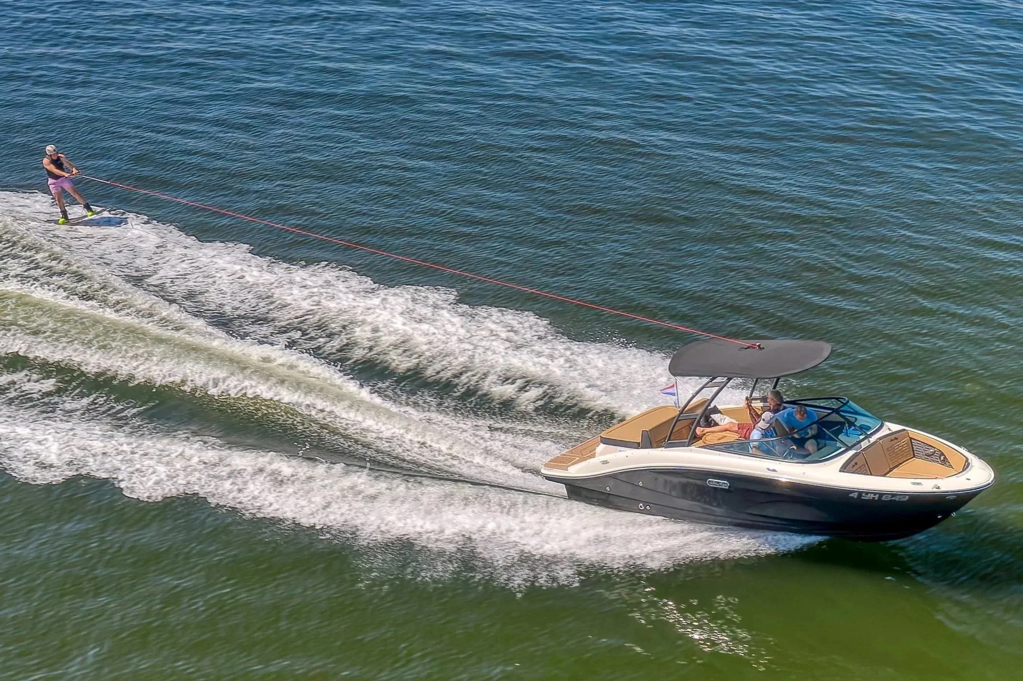 Een persoon wakeboarden achter een speedboot op het water.