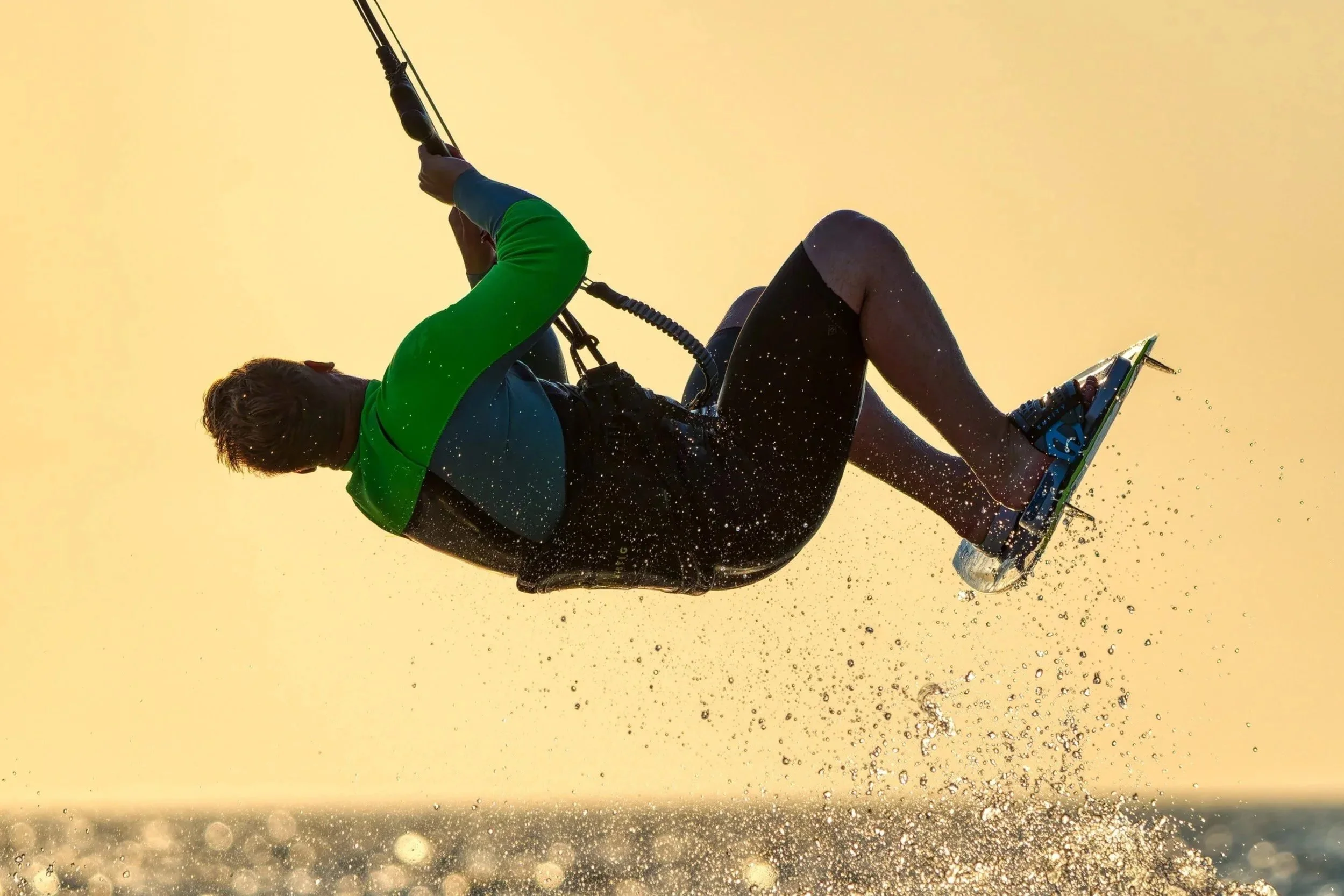 Person die achterover op een surfplank balanceert en over het water glijdt tijdens zonsopgang of zonsondergang.